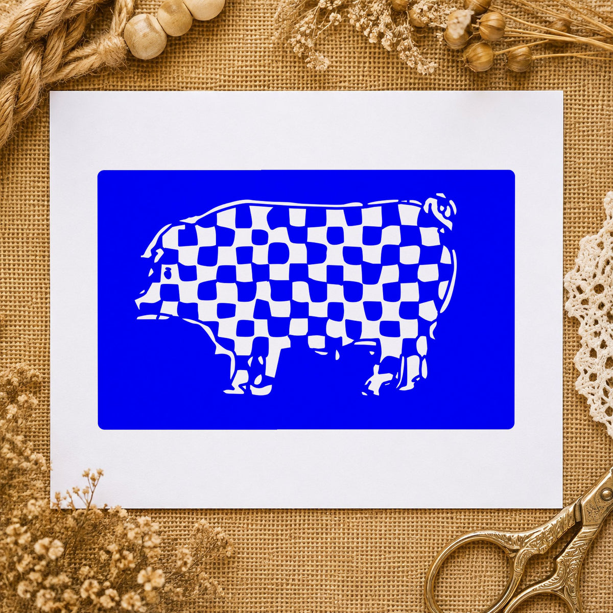 Checkered Pig Block Rubber Stamp impression in blue ink on white paper in a styled craft setting.