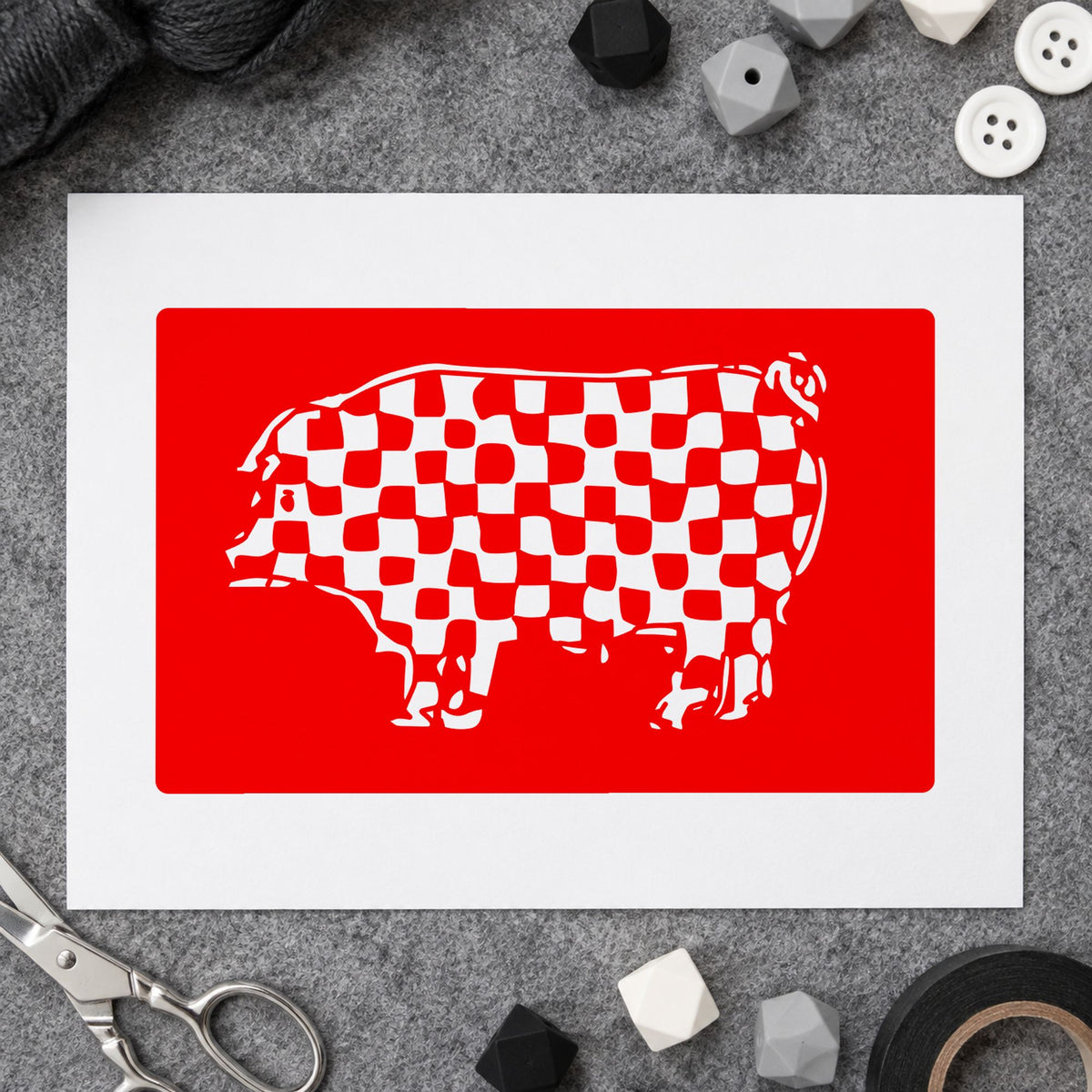 Checkered Pig Block Rubber Stamp impression in red ink on white paper in a styled craft setting.