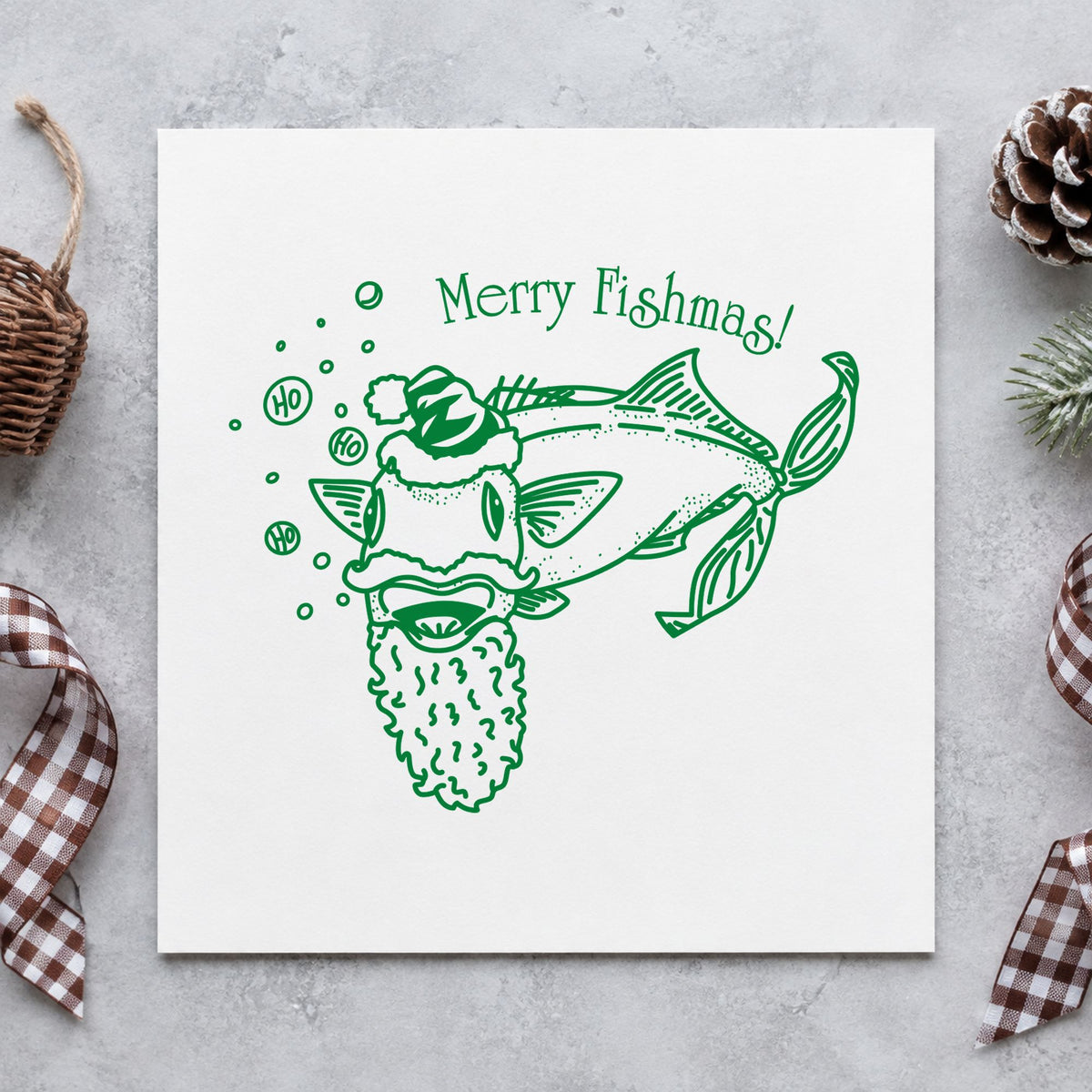 Merry Fishmas Catfish Rubber Stamp impression in green ink on white paper in a styled craft setting.
