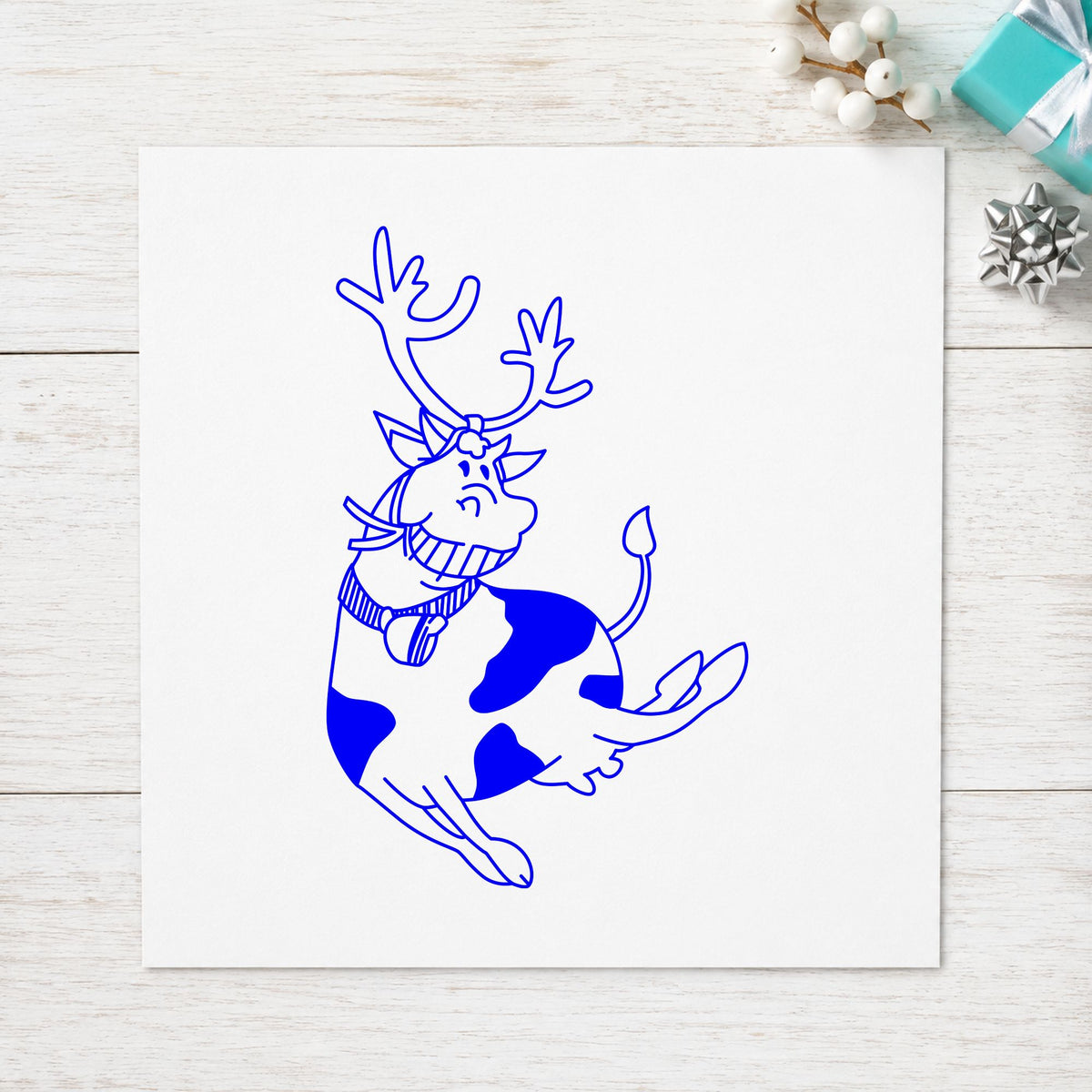 Blue funny christmas stamp impression featuring the leaping cow with reindeer antlers design on white paper.