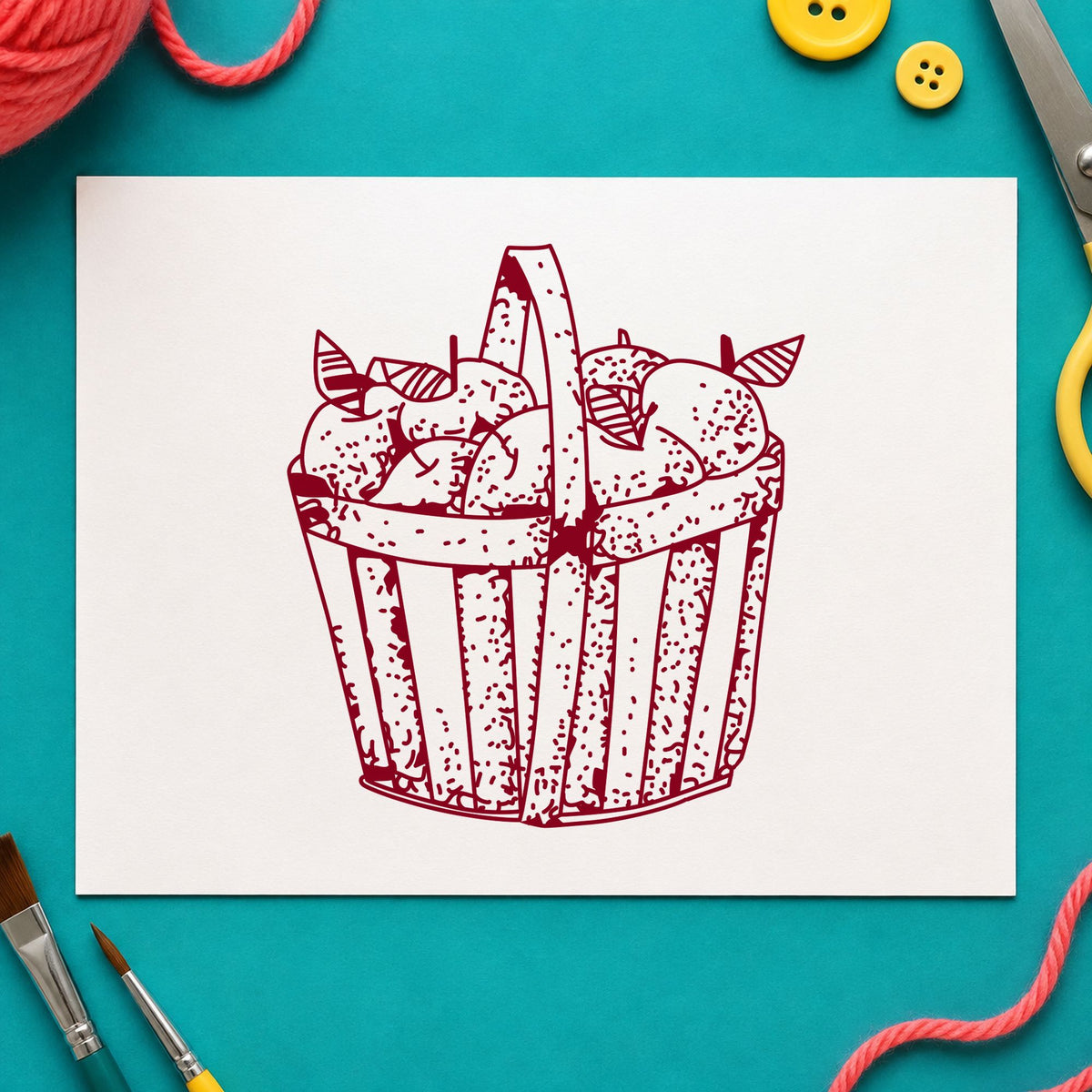 Slatted Apple Basket Rubber Stamp impression in burgundy ink on white paper in a styled craft setting.