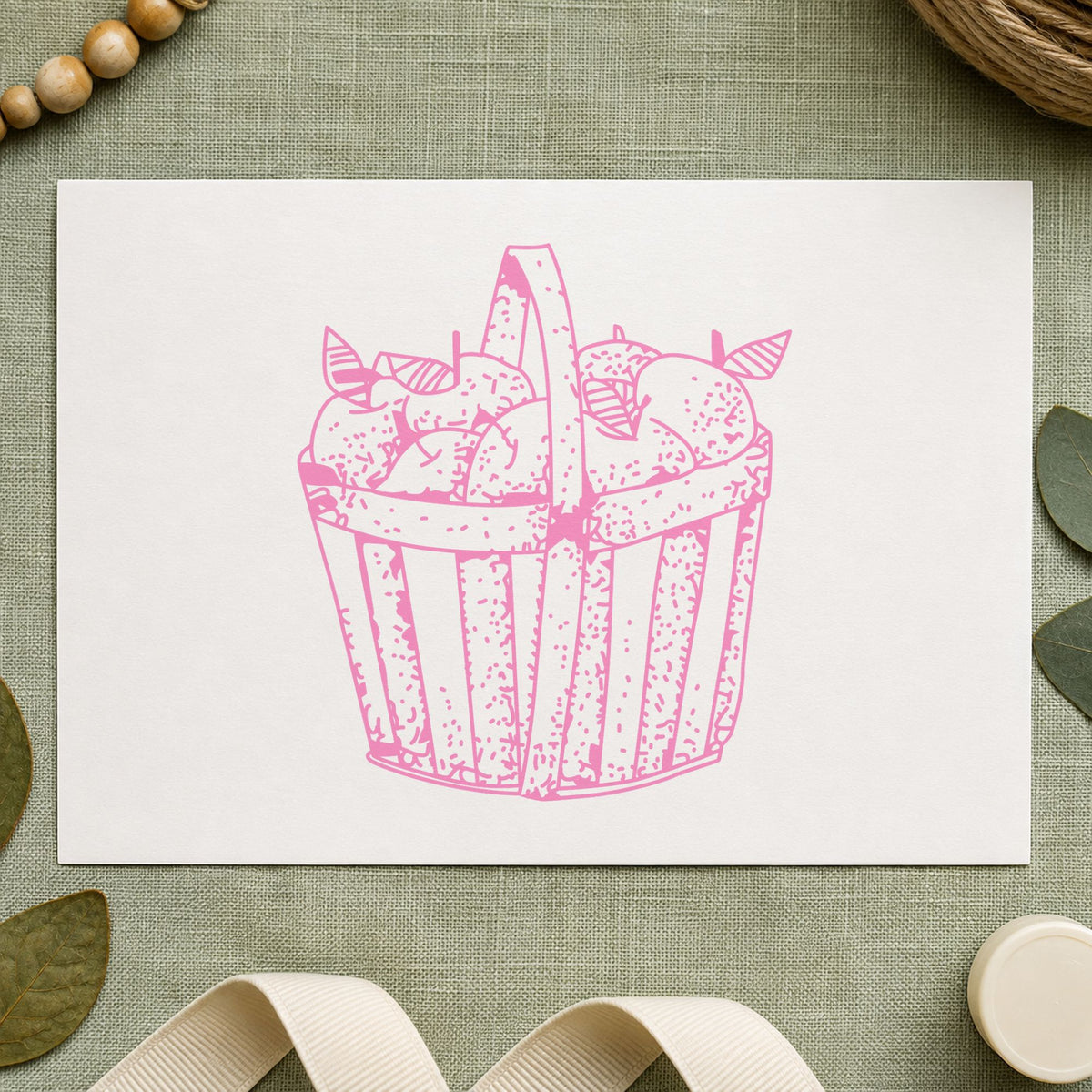 Slatted Apple Basket Rubber Stamp impression in pink ink on white paper in a styled craft setting.