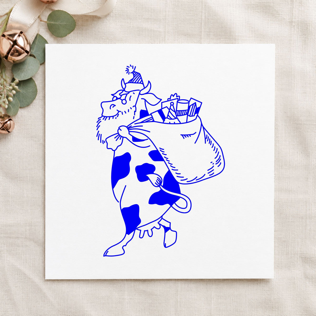 Blue christmas scrapbook stamp impression featuring the santa cow with gift sack large design on white paper.