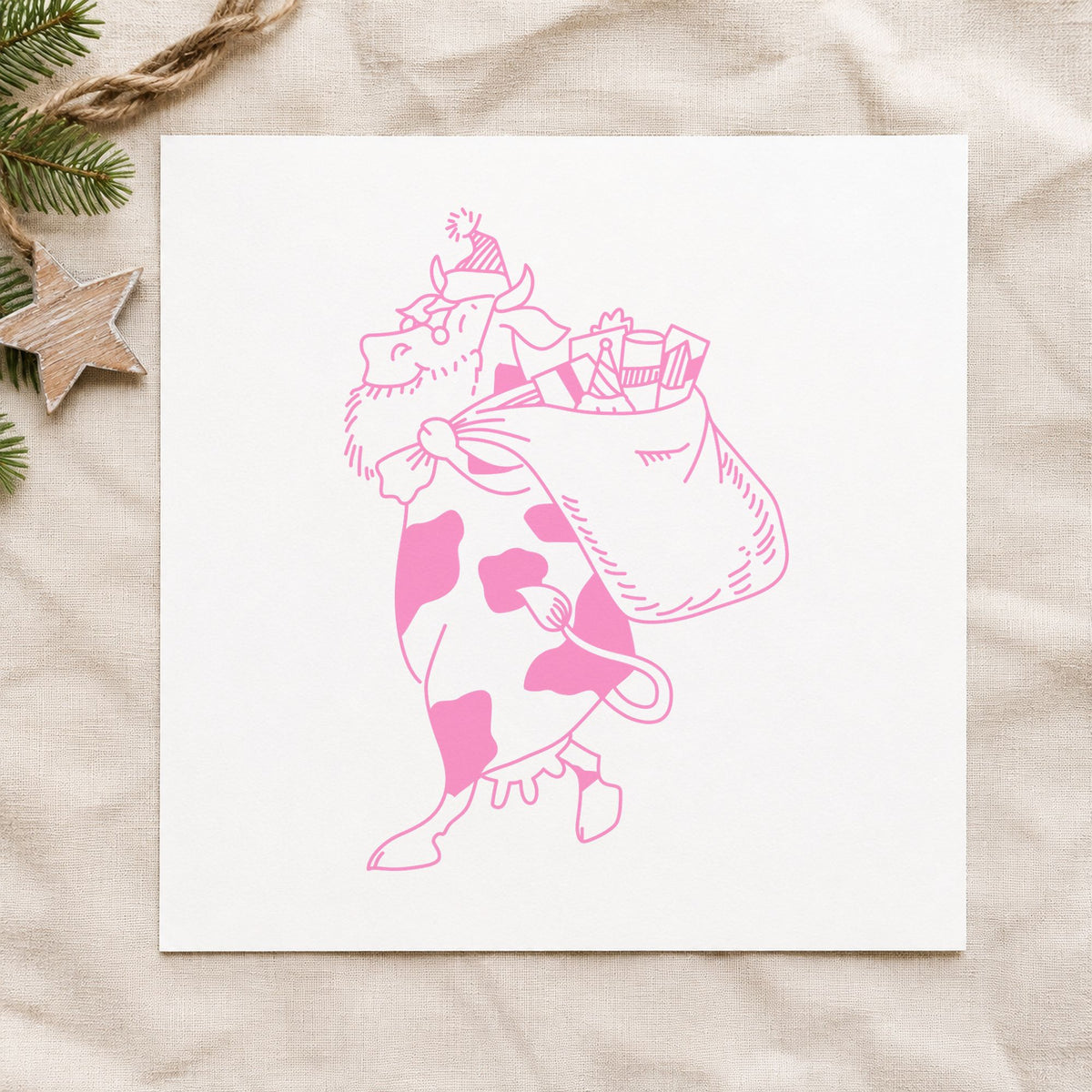 Santa Cow with Gift Sack Rubber Stamp Small impression in pink ink on white paper in a styled craft setting.