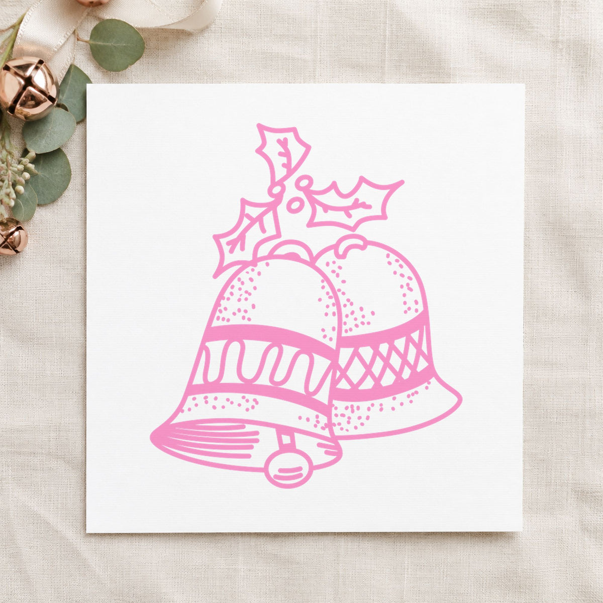 Christmas Bells with Mistletoe Rubber Stamp impression in pink ink on white paper in a styled craft setting.
