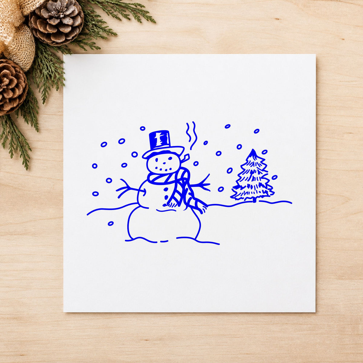 Snowman in Winter Landscape Rubber Stamp impression in blue ink on white paper in a styled craft setting.