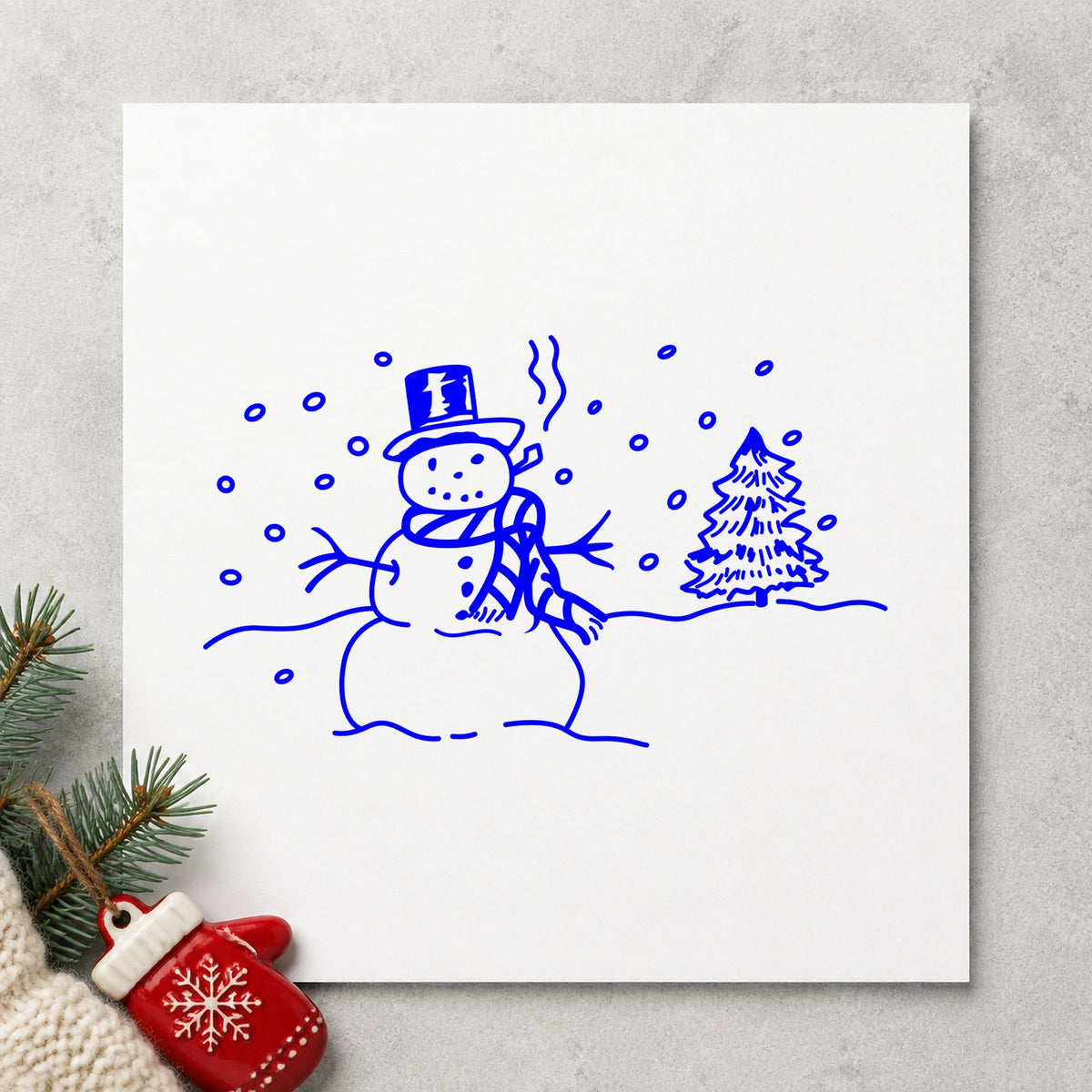 Blue winter card making stamp impression featuring the snowman in winter landscape design on white paper.