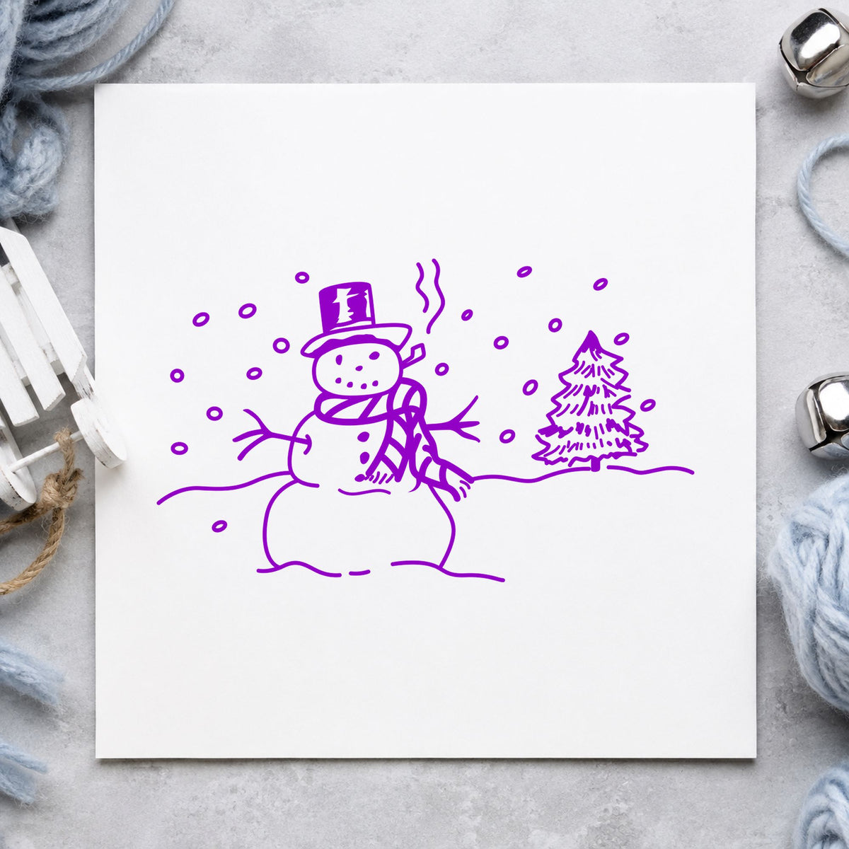 Snowman in Winter Landscape Rubber Stamp impression in purple ink on white paper in a styled craft setting.