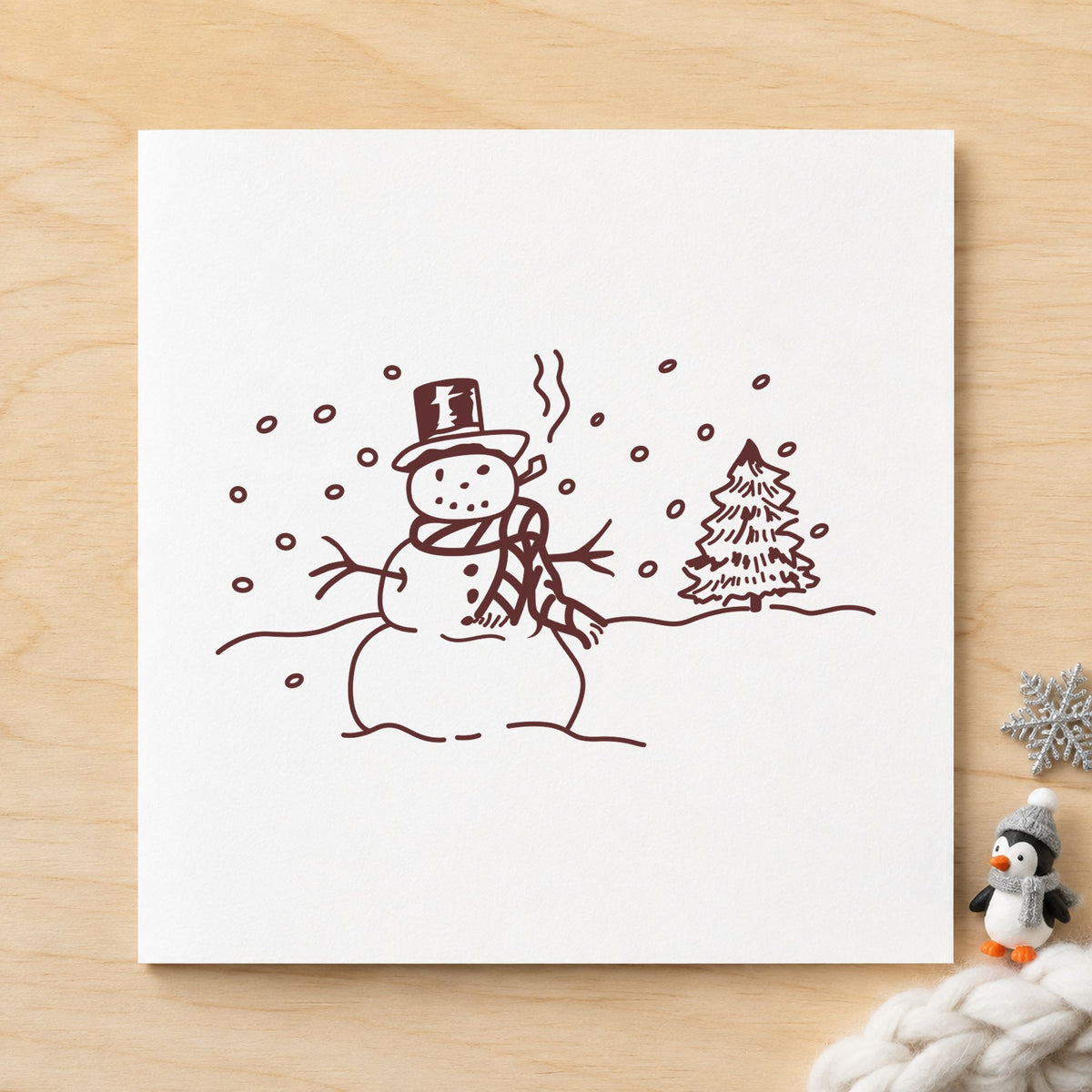 Snowman in Winter Landscape Rubber Stamp impression in brown ink on white paper in a styled craft setting.