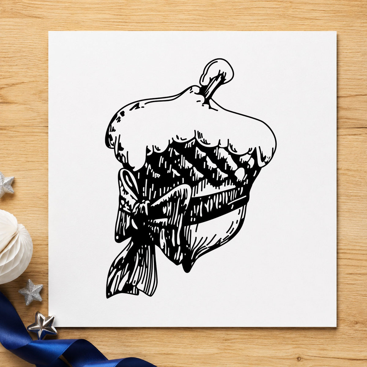 Black impression from a acorn rubber stamp, featuring the snowy acorn with bow christmas design on white paper.