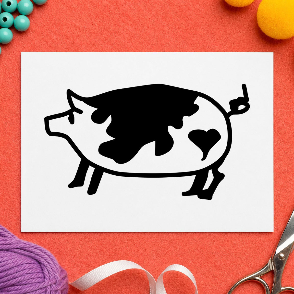 Black impression from a pig rubber stamp, featuring the spotted pig with heart design on white paper.