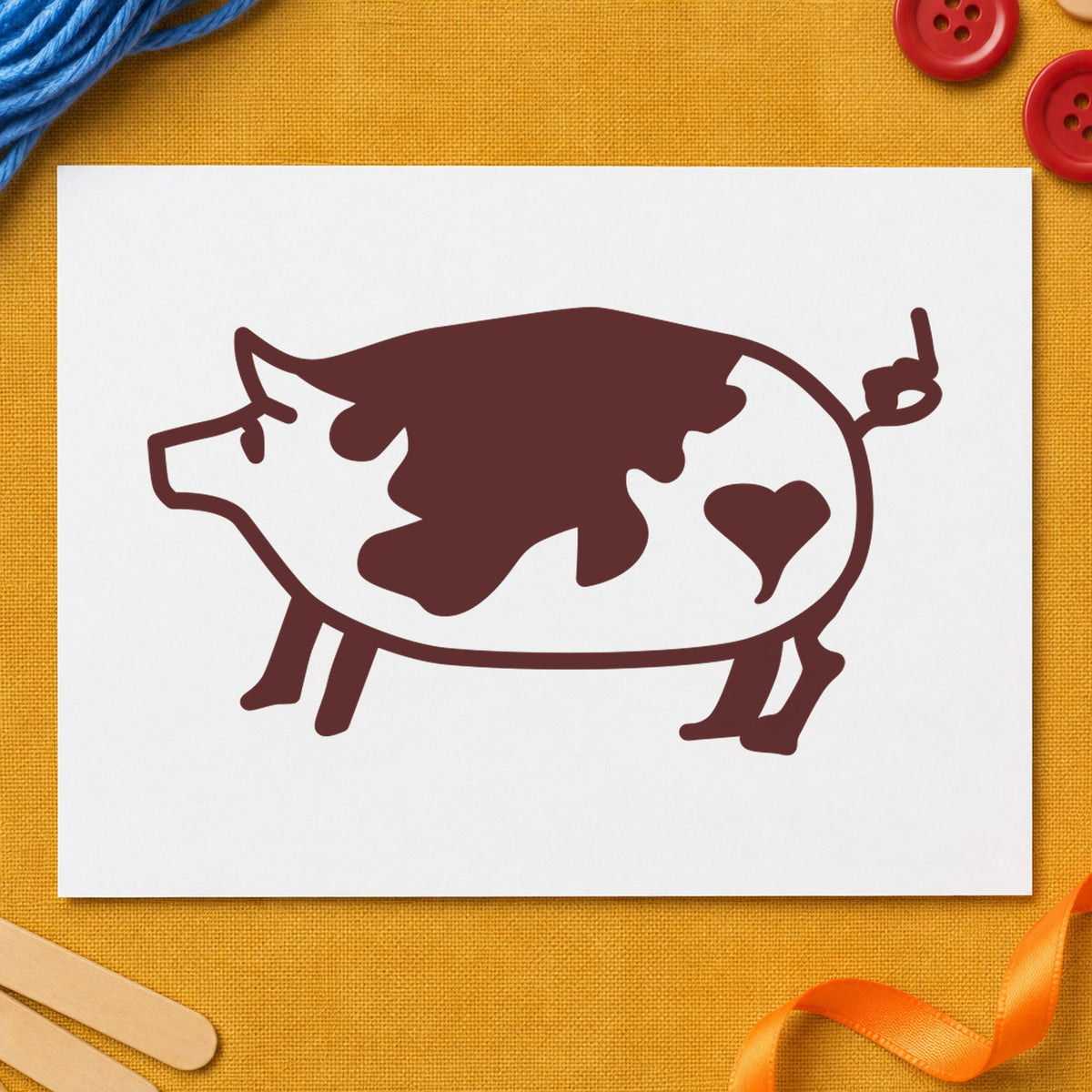 Spotted Pig with Heart Rubber Stamp impression in brown ink on white paper in a styled craft setting.