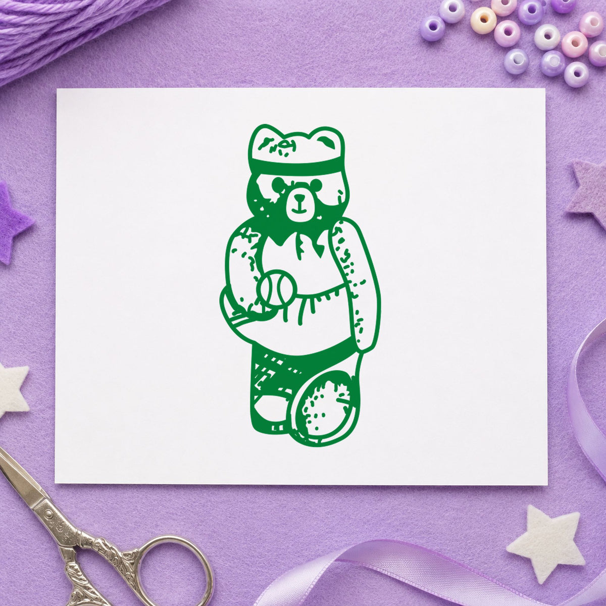 Girl Tennis Bear Rubber Stamp impression in green ink on white paper in a styled craft setting.