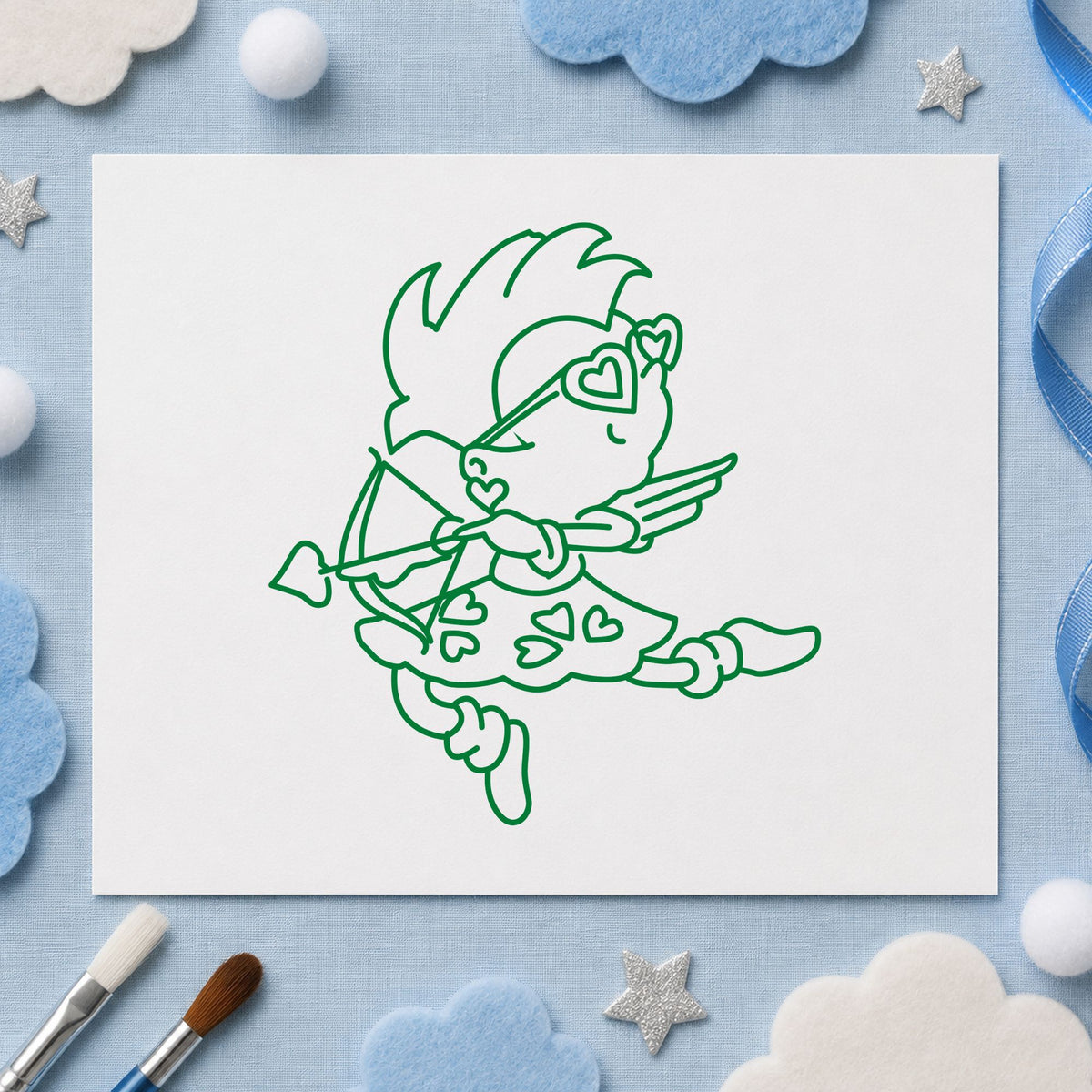 Cupid with Heart Sunglasses Rubber Stamp impression in green ink on white paper in a styled craft setting.