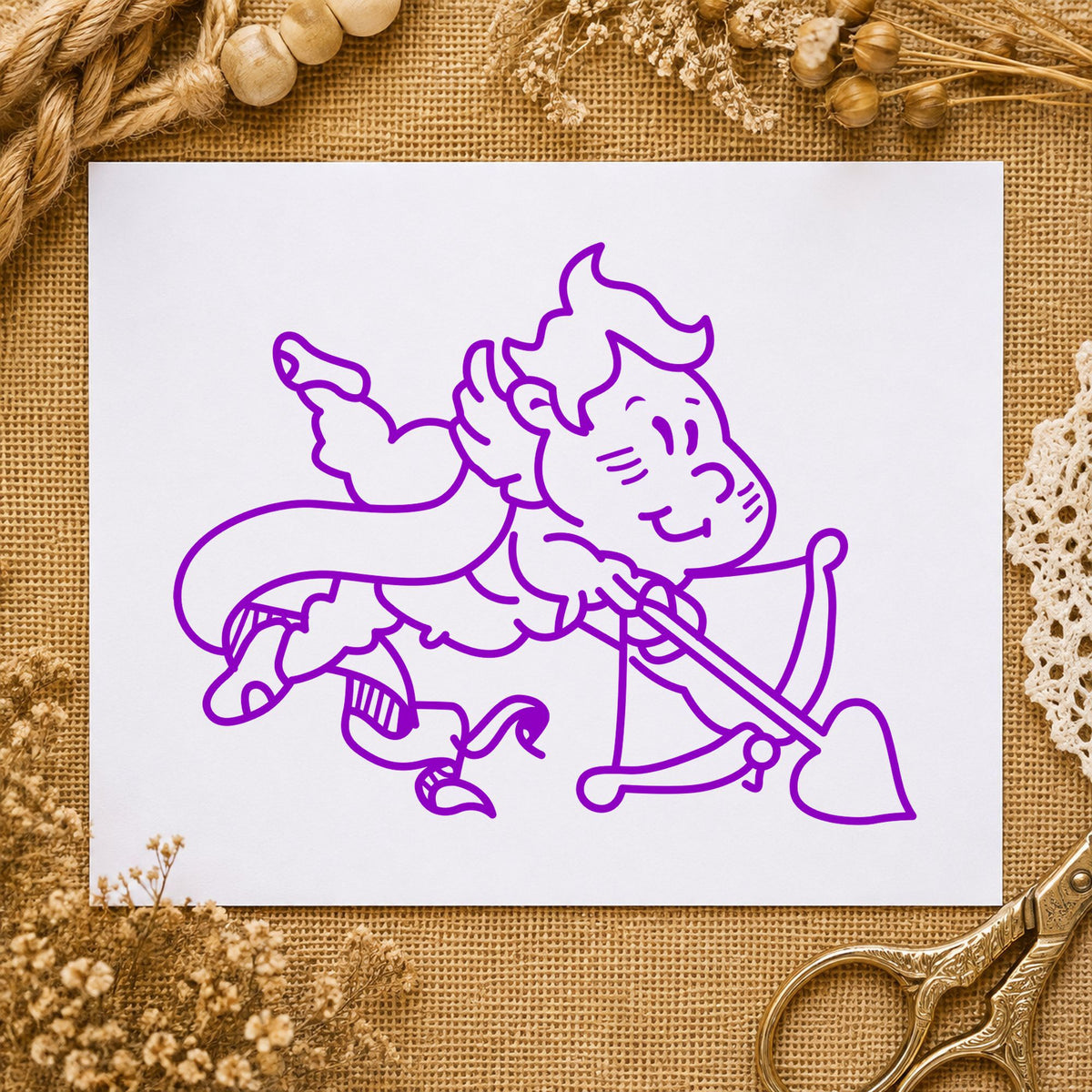 Cupid Shooting Heart Arrow Rubber Stamp impression in purple ink on white paper in a styled craft setting.