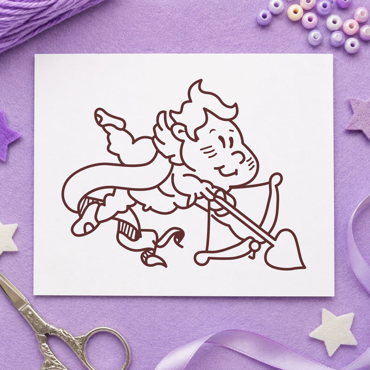 Cupid Shooting Heart Arrow Rubber Stamp impression in brown ink on white paper in a styled craft setting.
