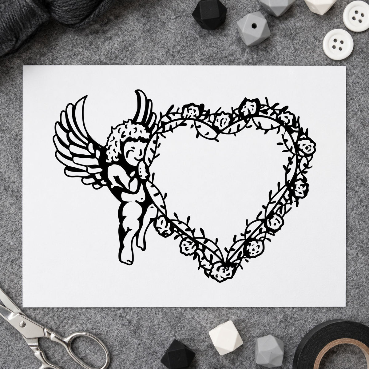 Black impression from a cupid craft stamp, featuring the cupid holding vine heart design on white paper.