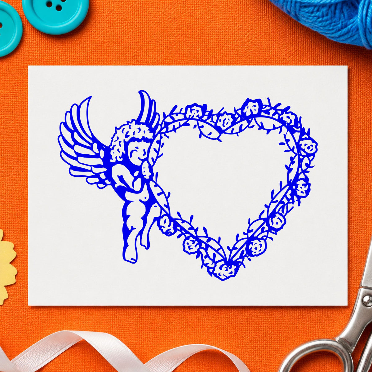 Cupid Holding Vine Heart Rubber Stamp impression in blue ink on white paper in a styled craft setting.