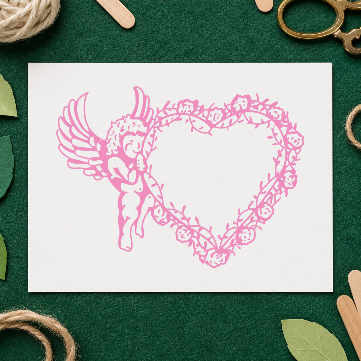 Cupid Holding Vine Heart Rubber Stamp impression in pink ink on white paper in a styled craft setting.