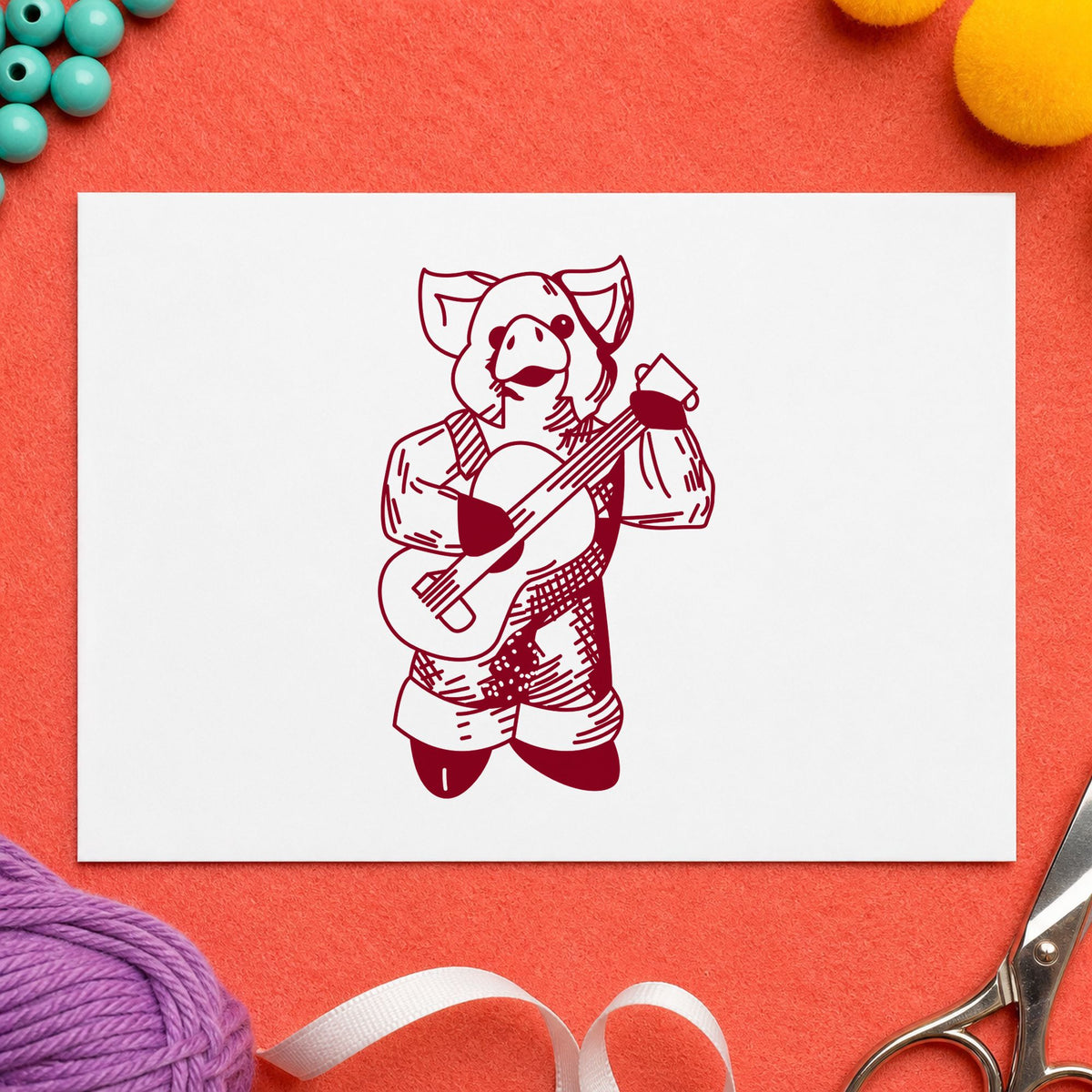 Banjo Playing Pig Rubber Stamp impression in burgundy ink on white paper in a styled craft setting.