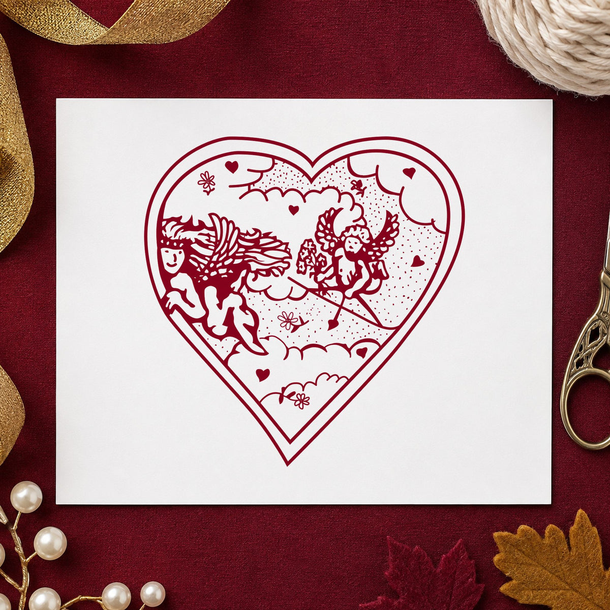 Heart with Two Cupids Rubber Stamp impression in burgundy ink on white paper in a styled craft setting.