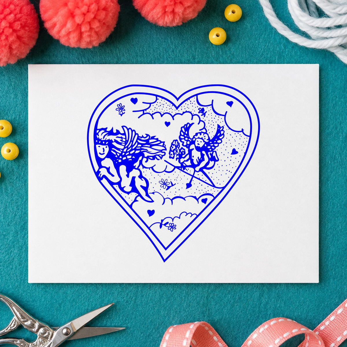 Blue valentine card making stamp impression featuring the heart with two cupids design on white paper.