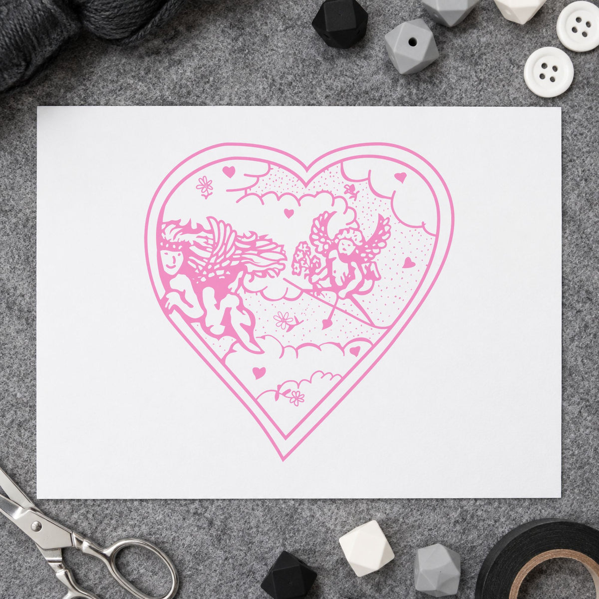 Heart with Two Cupids Rubber Stamp impression in pink ink on white paper in a styled craft setting.
