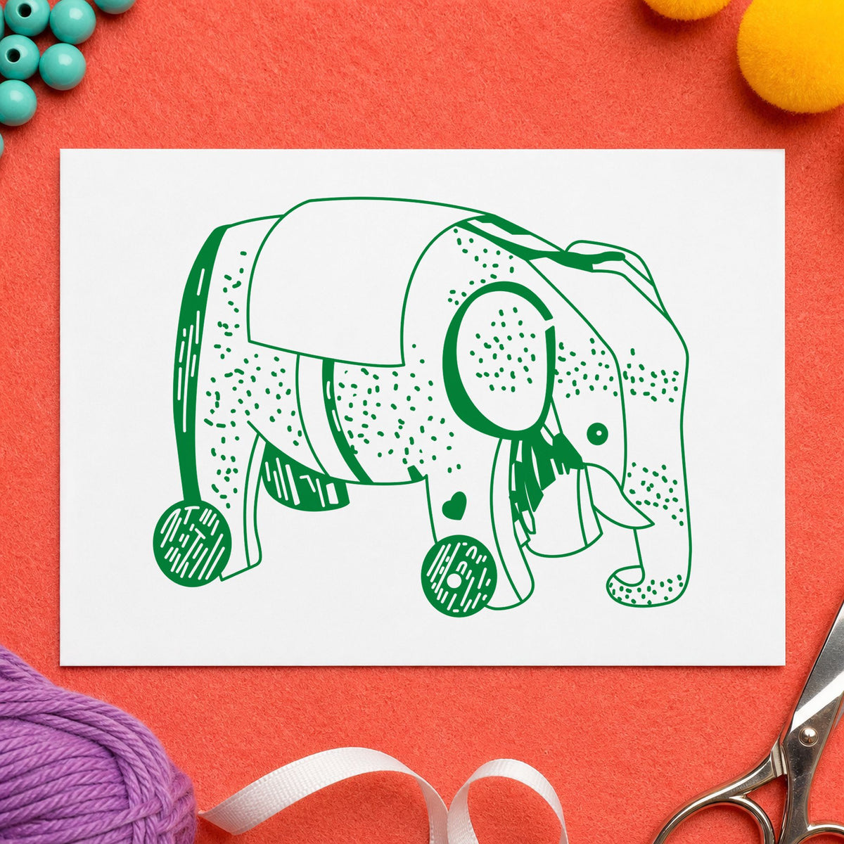 Wheeled Elephant Toy Rubber Stamp impression in green ink on white paper in a styled craft setting.