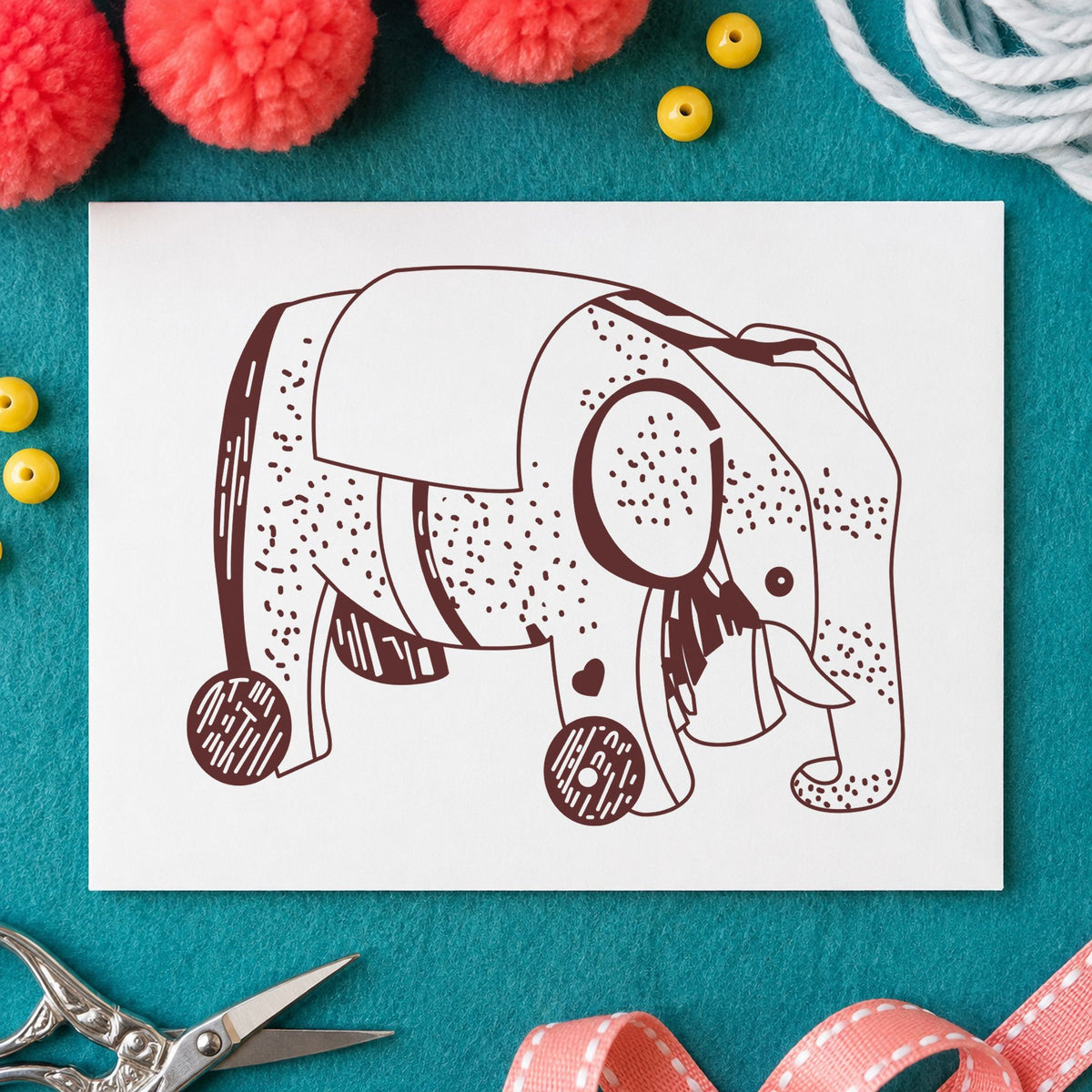 Wheeled Elephant Toy Rubber Stamp impression in brown ink on white paper in a styled craft setting.