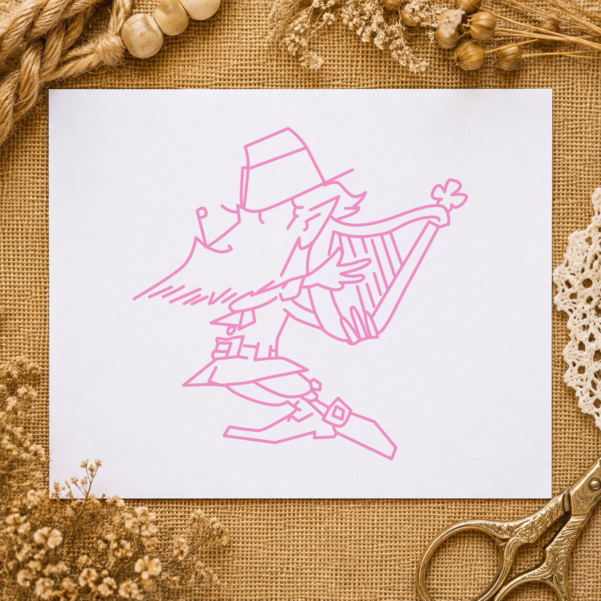 Leprechaun Playing Harp Rubber Stamp impression in pink ink on white paper in a styled craft setting.