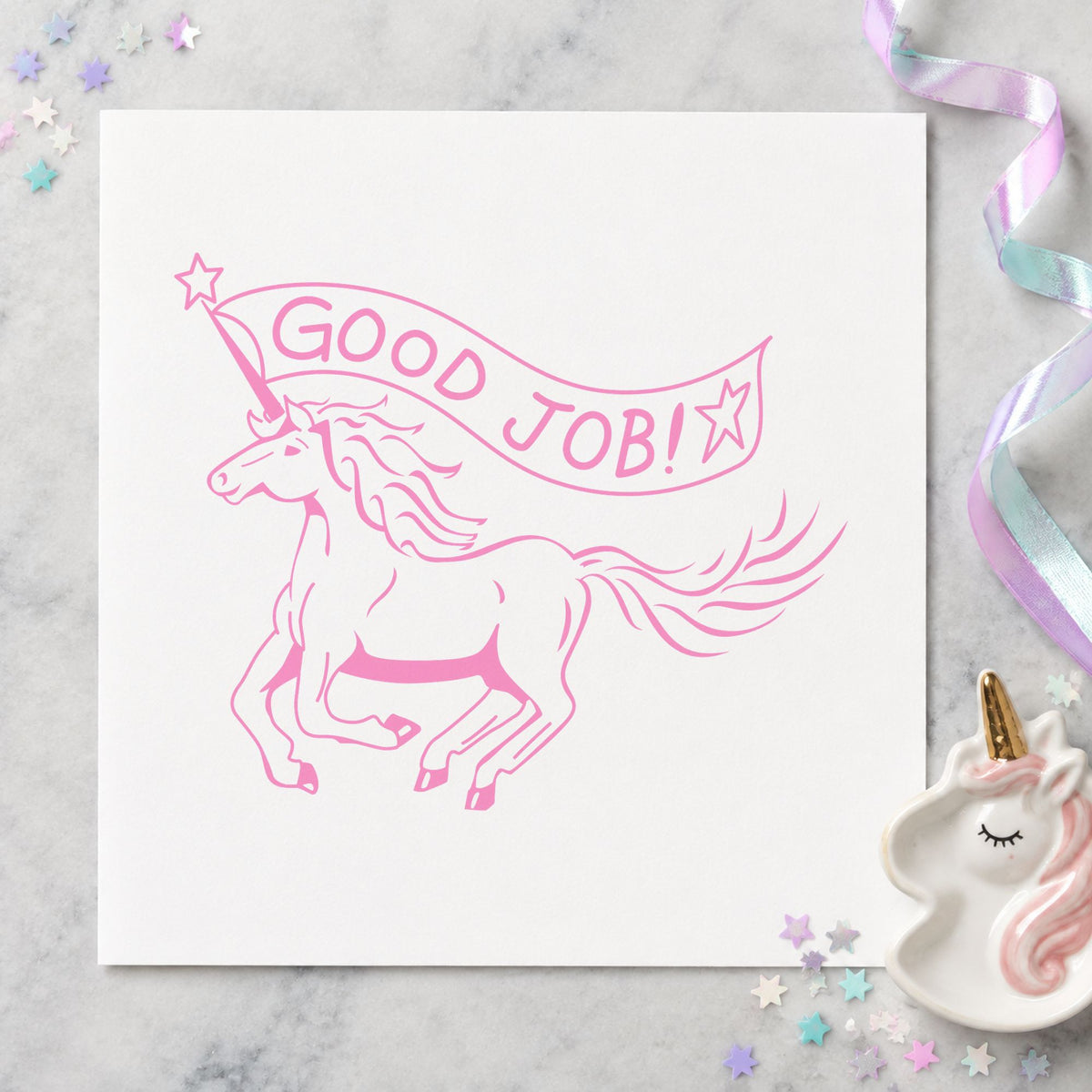 Good Job Unicorn Rubber Stamp impression in pink ink on white paper in a styled craft setting.