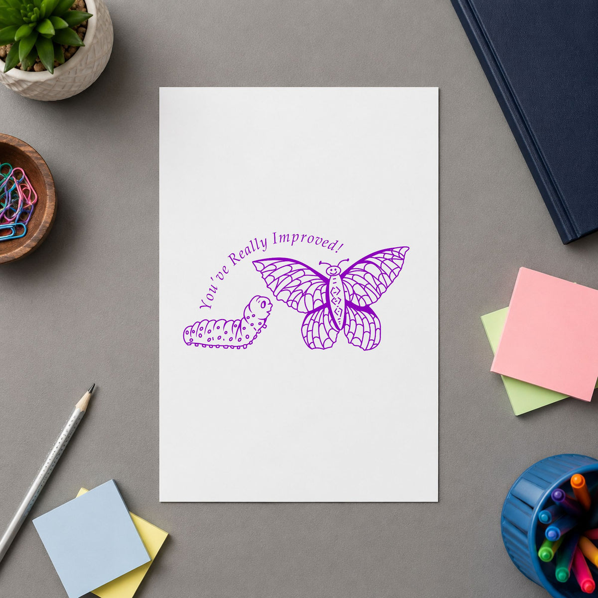 Youve Really Improved Butterfly and Caterpillar Rubber Stamp impression in purple ink on white paper in a styled craft setting.