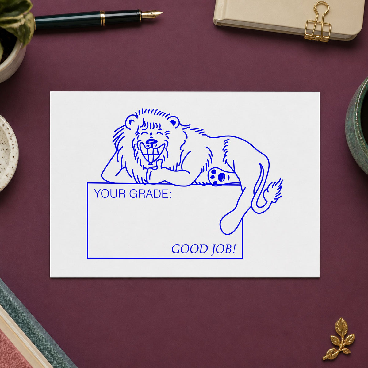 Your Grade Good Job Lion Rubber Stamp impression in blue ink on white paper in a styled craft setting.