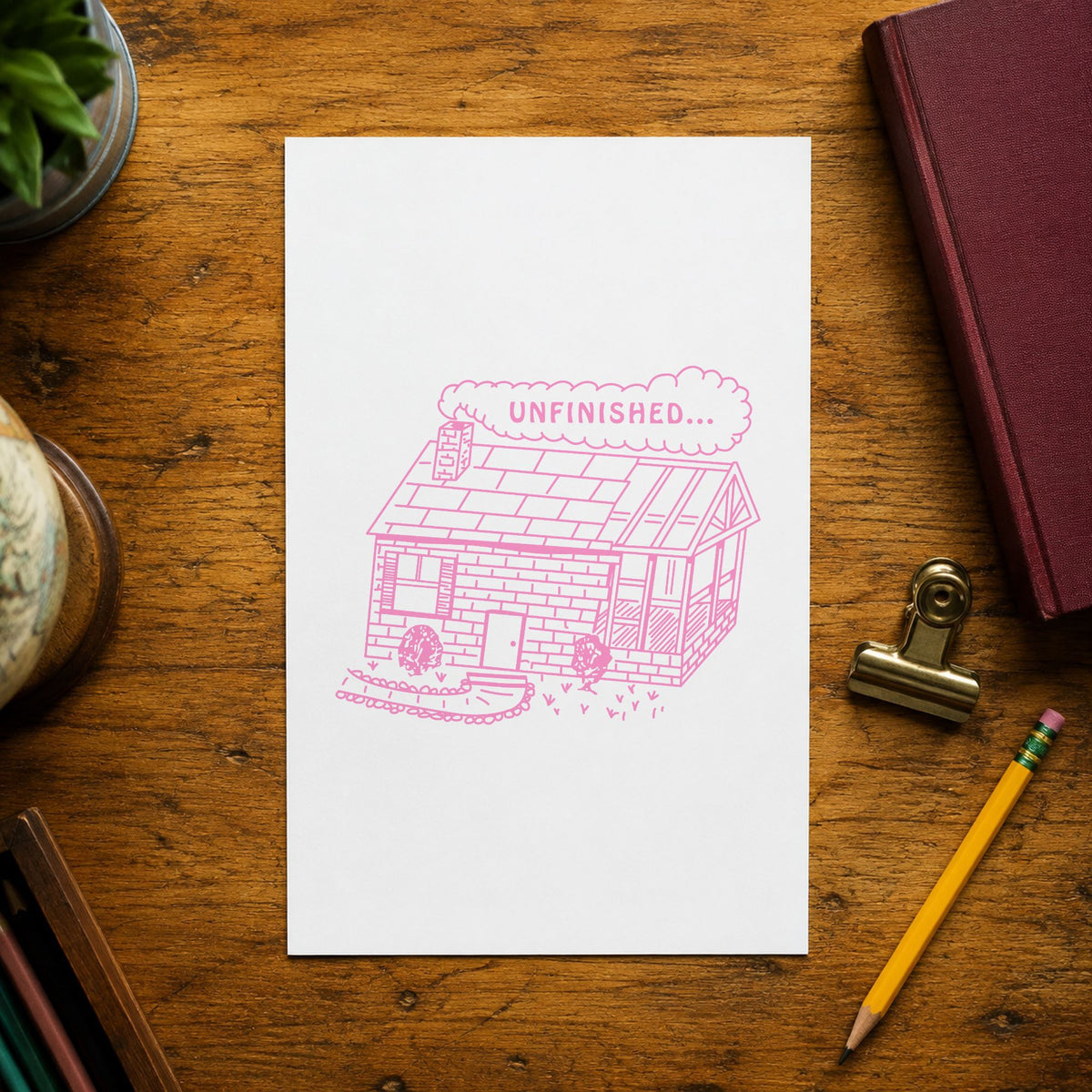 Unfinished Work Reminder Rubber Stamp impression in pink ink on white paper in a styled craft setting.