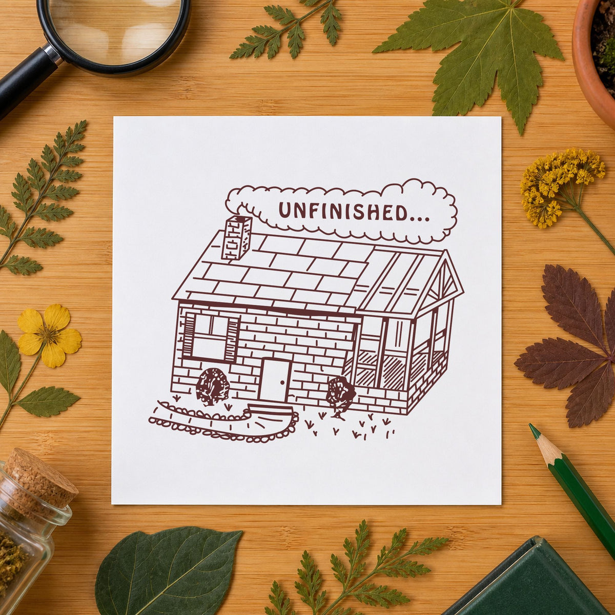 Unfinished Work Reminder Rubber Stamp impression in brown ink on white paper in a styled craft setting.
