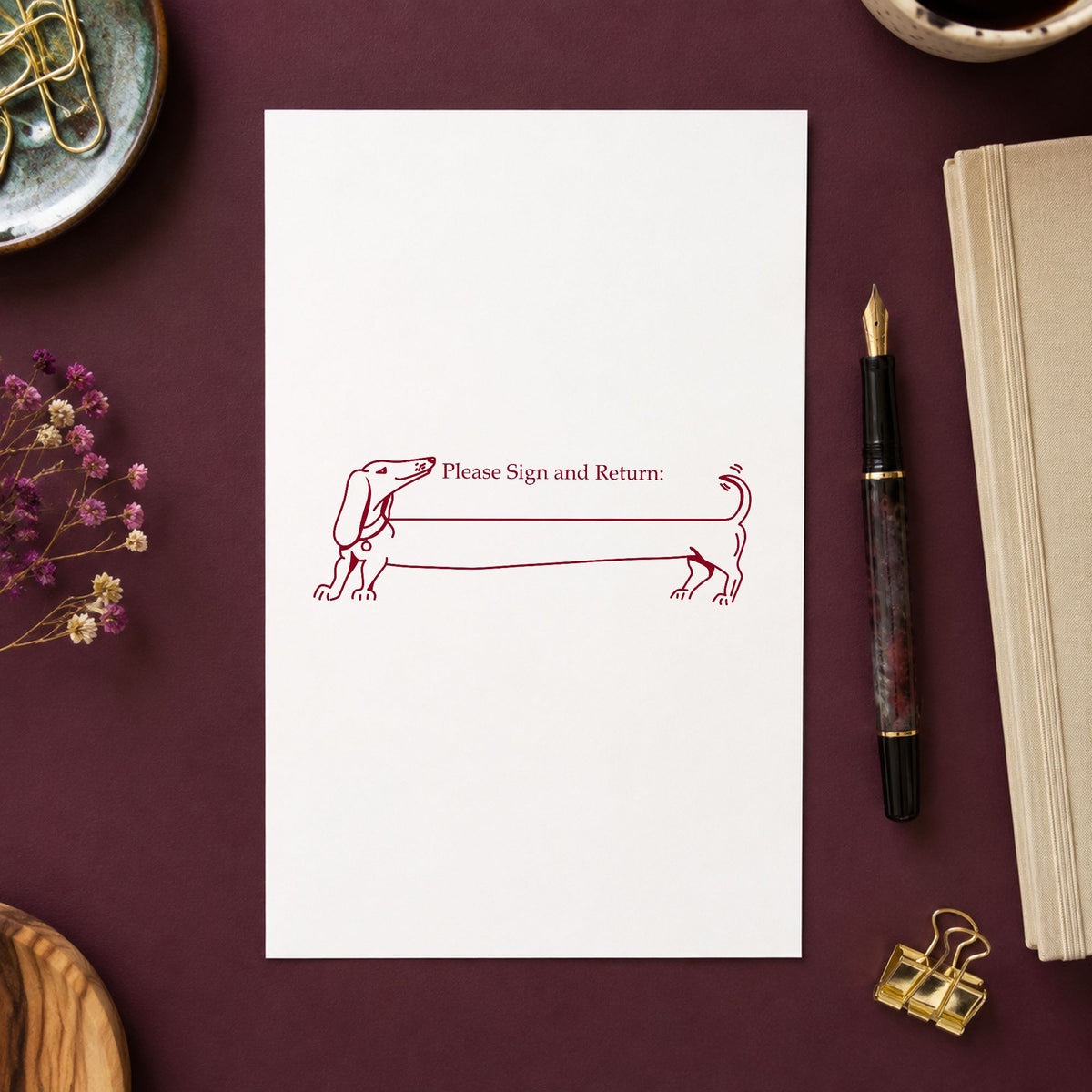 Blank Award Ribbon Rubber Stamp impression in burgundy ink on white paper in a styled craft setting.