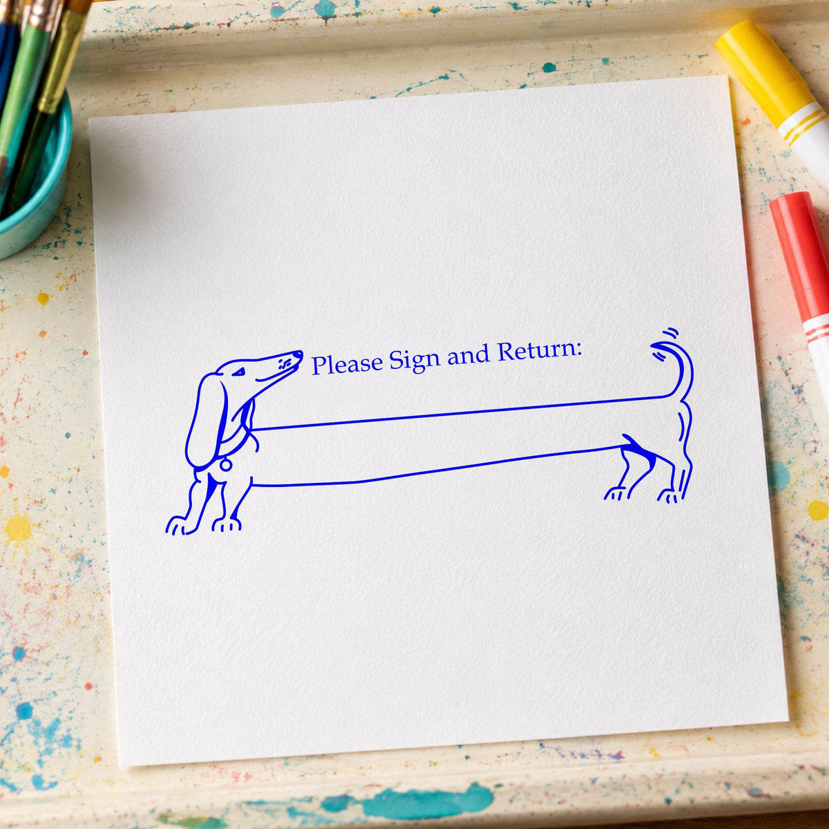 Please Sign and Return Dog Rubber Stamp impression in blue ink on white paper in a styled craft setting.