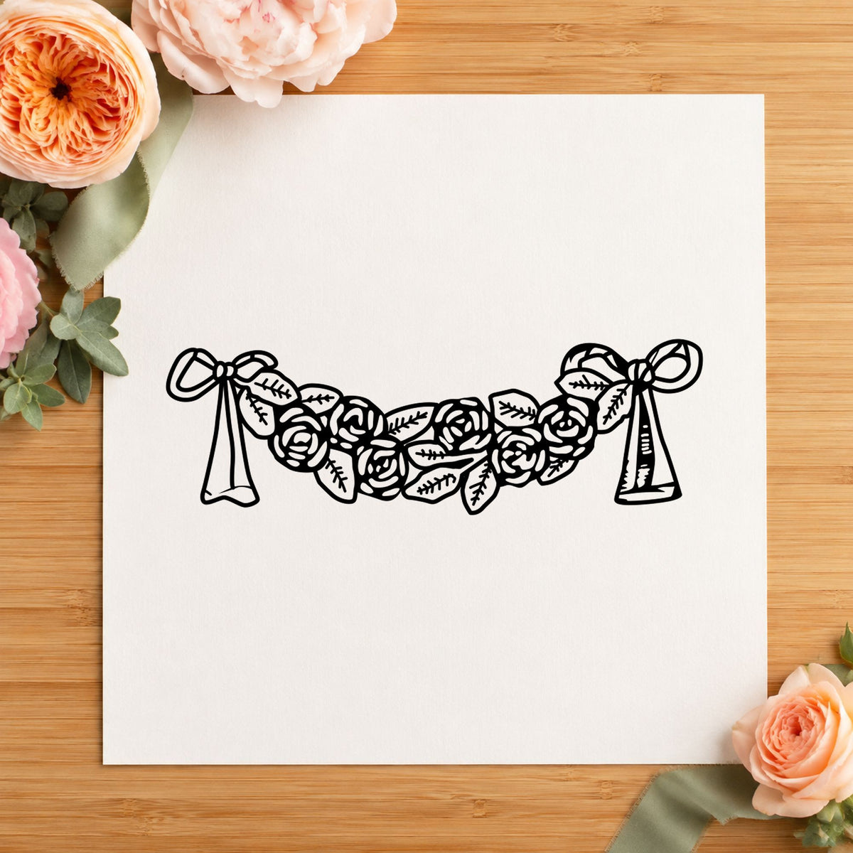 Rose Swag with Bows Rubber Stamp impression in black ink on white paper in a styled craft setting.