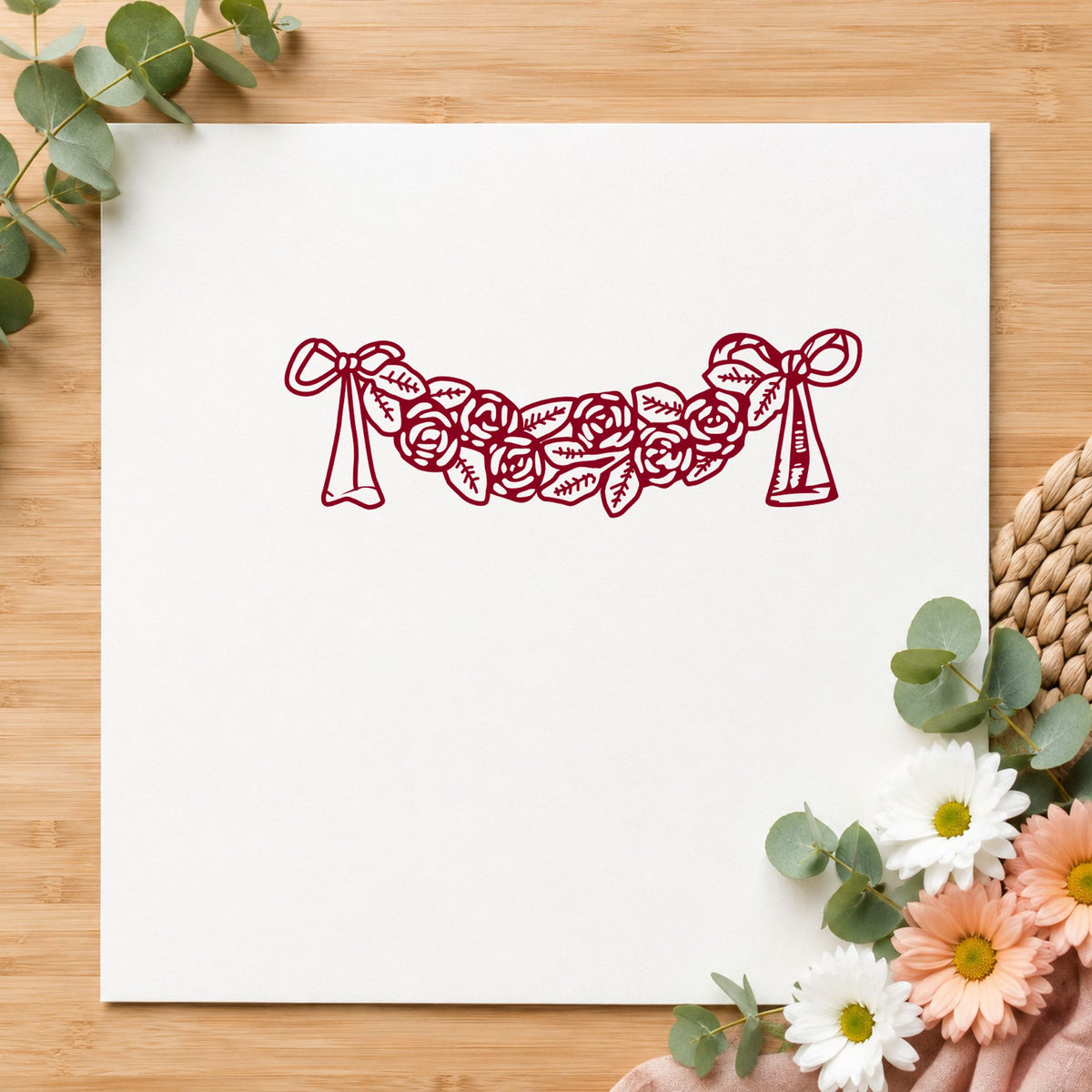 Rose Swag with Bows Rubber Stamp impression in burgundy ink on white paper in a styled craft setting.
