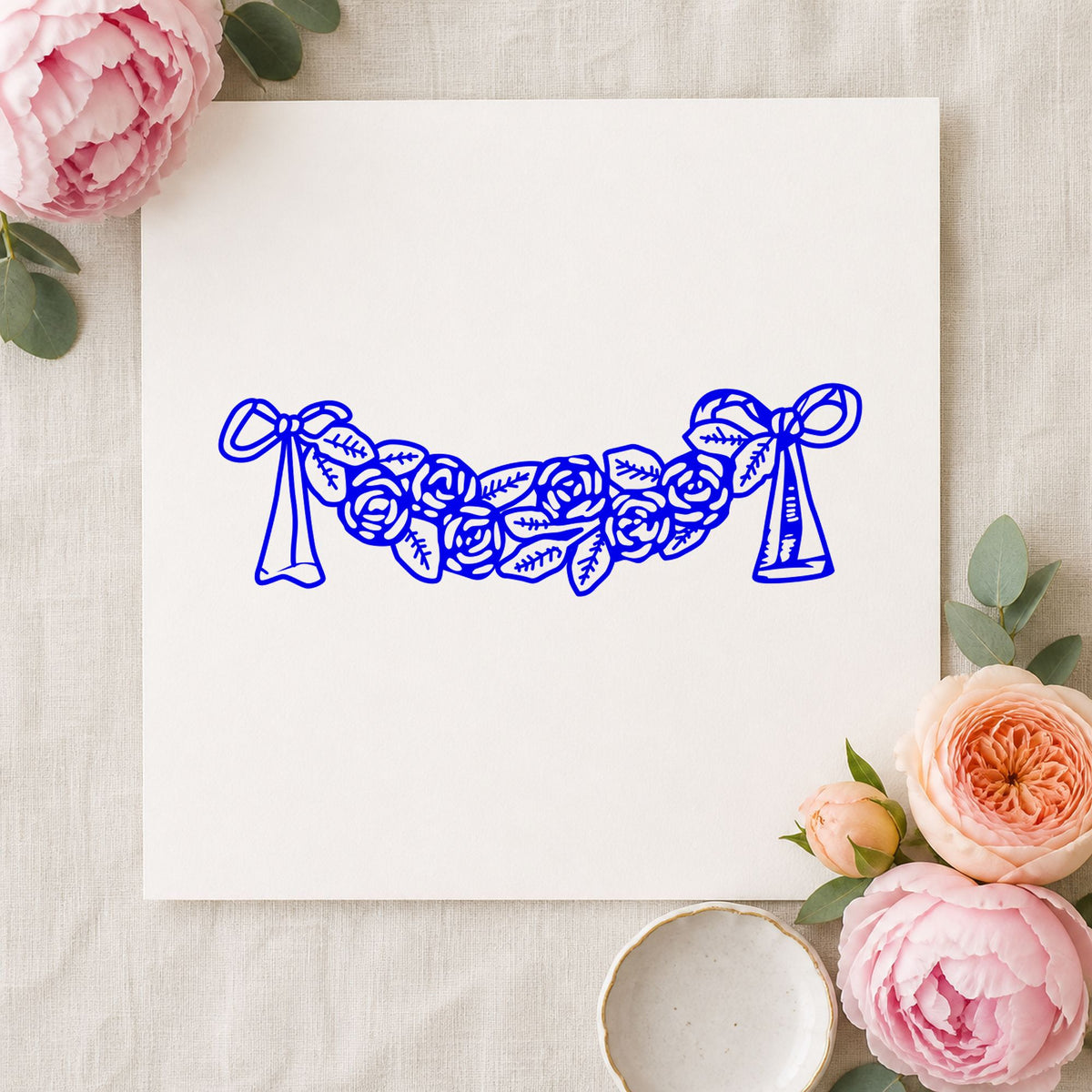 Rose Swag with Bows Rubber Stamp impression in blue ink on white paper in a styled craft setting.