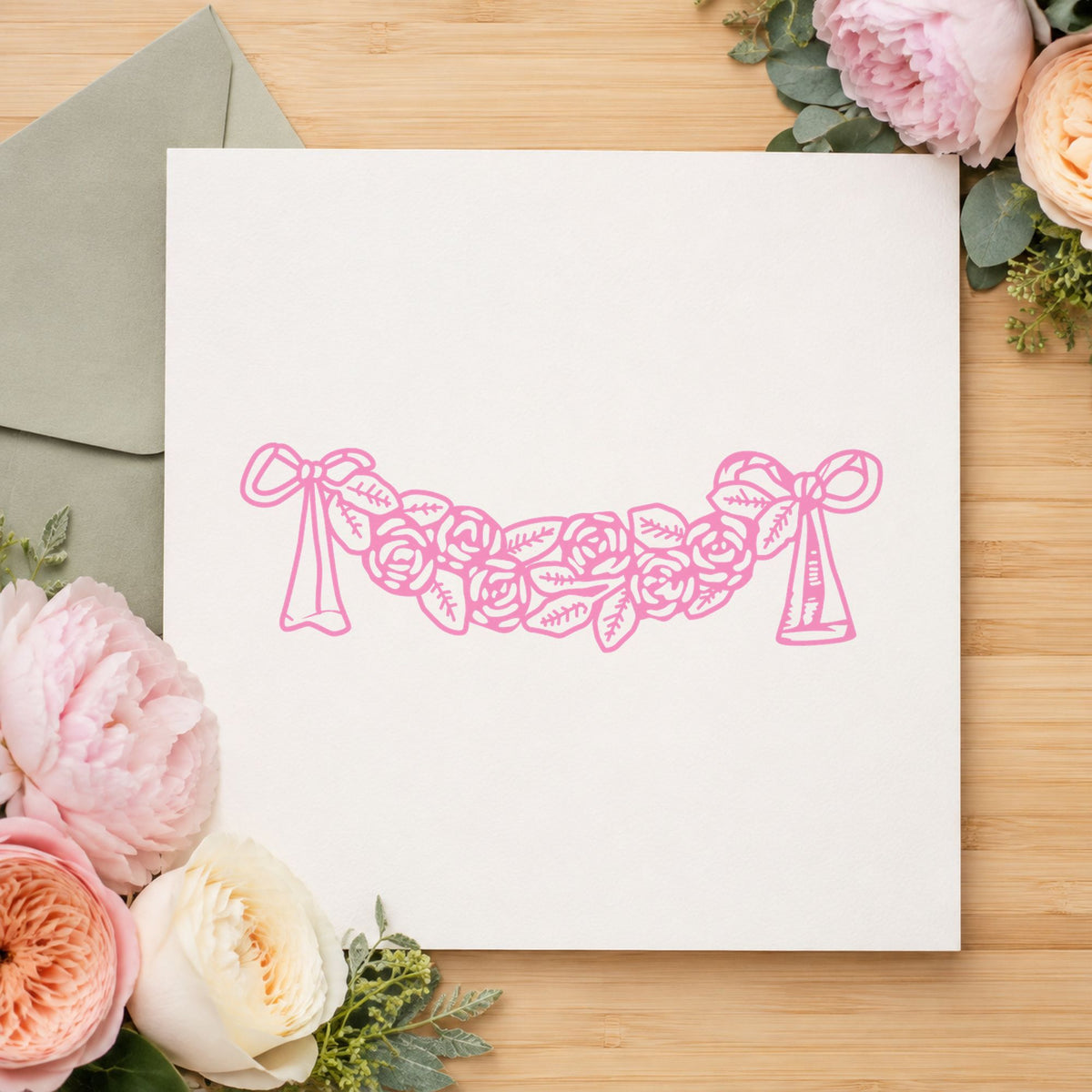 Rose Swag with Bows Rubber Stamp impression in pink ink on white paper in a styled craft setting.