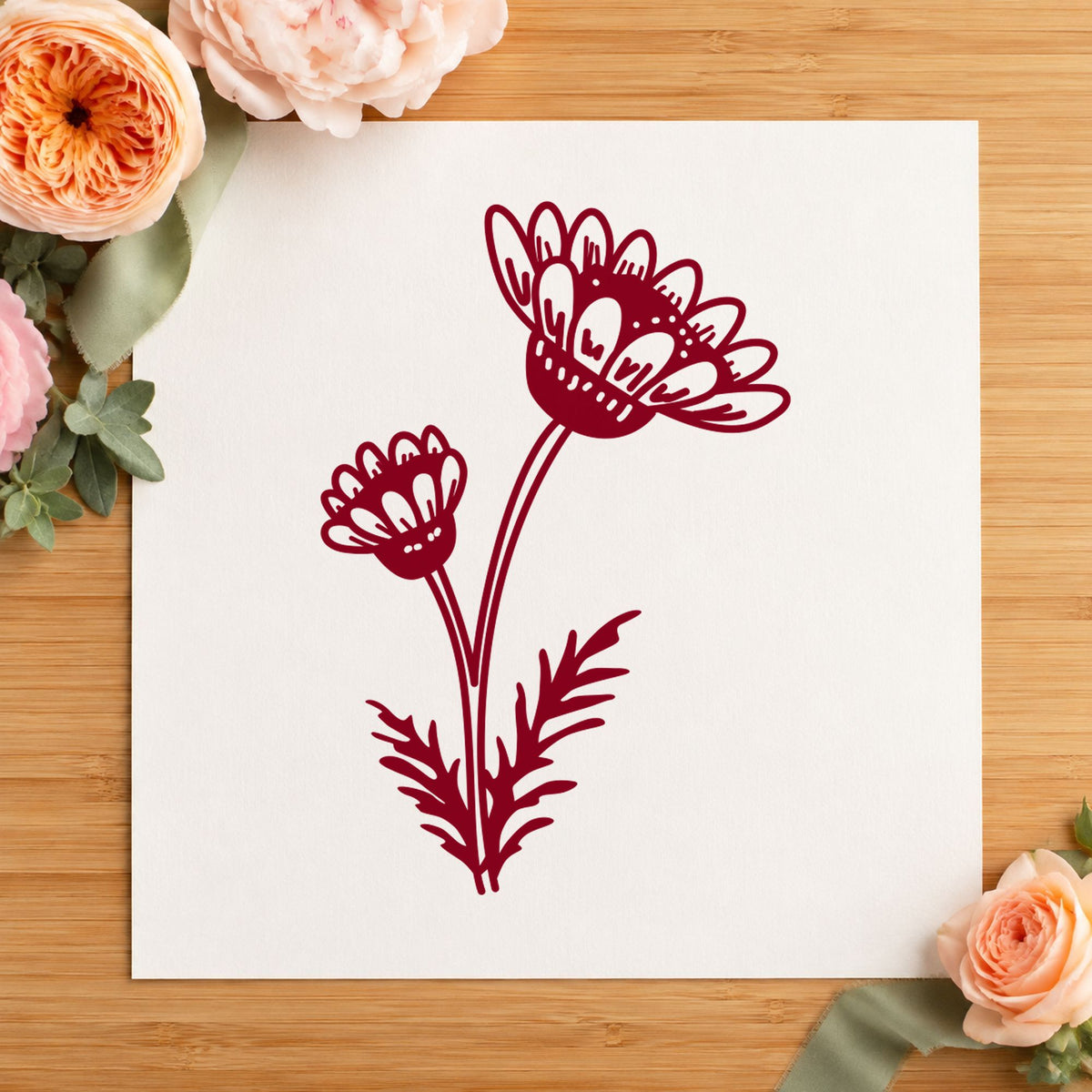 Two Daisies on a Stem Rubber Stamp impression in burgundy ink on white paper in a styled craft setting.
