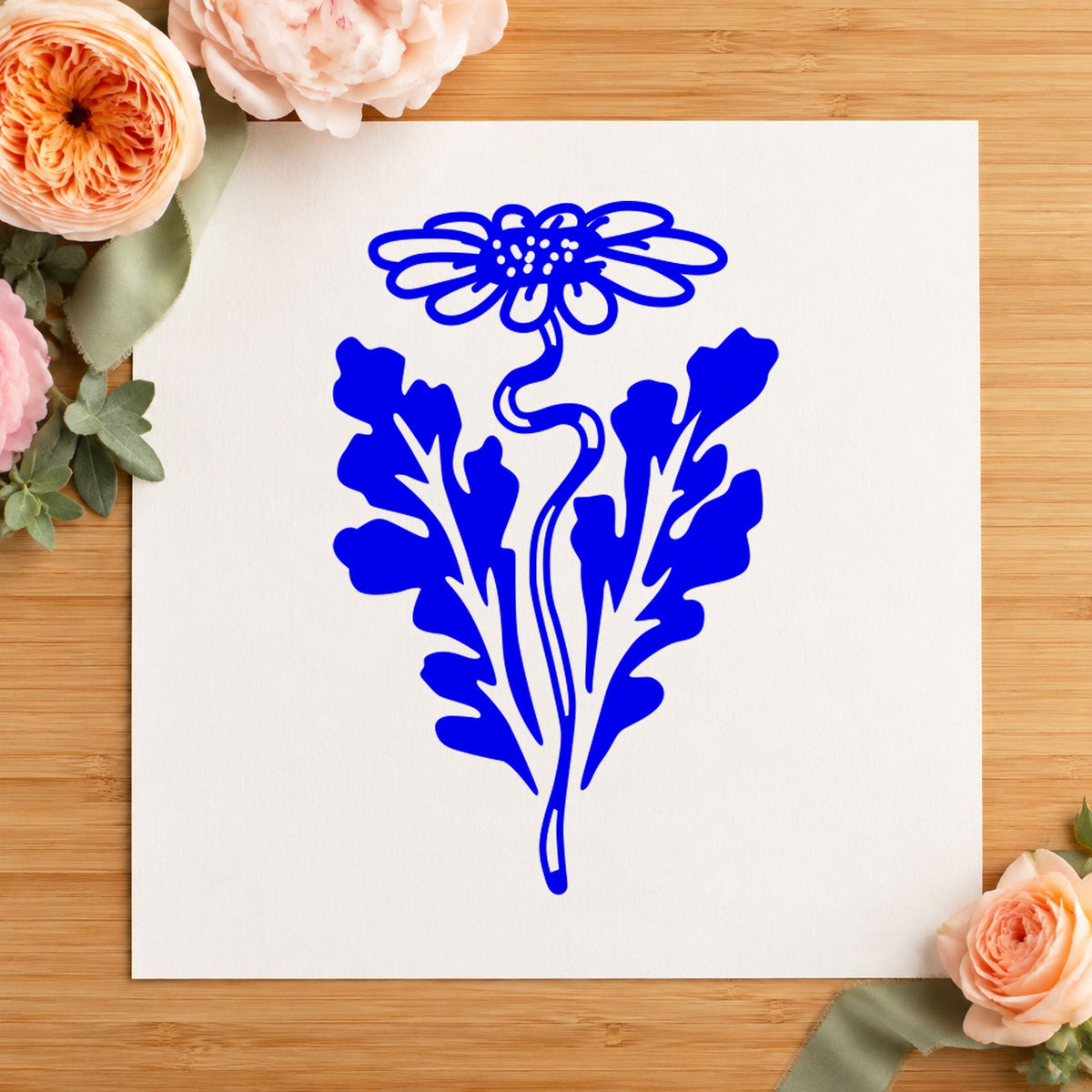 Daisy with Leaf Rubber Stamp impression in blue ink on white paper in a styled craft setting.