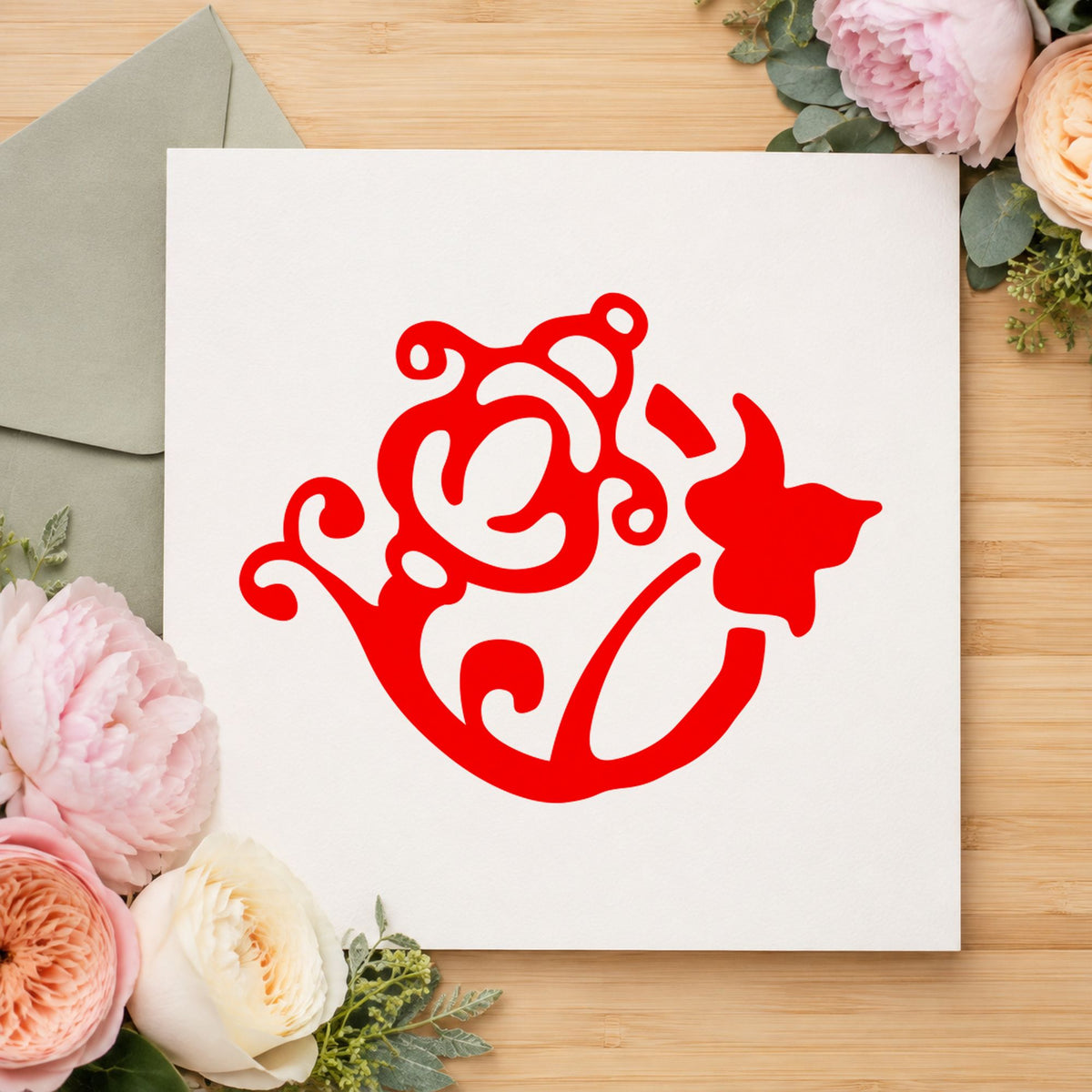 Flower and Watering Can Rubber Stamp impression in red ink on white paper in a styled craft setting.