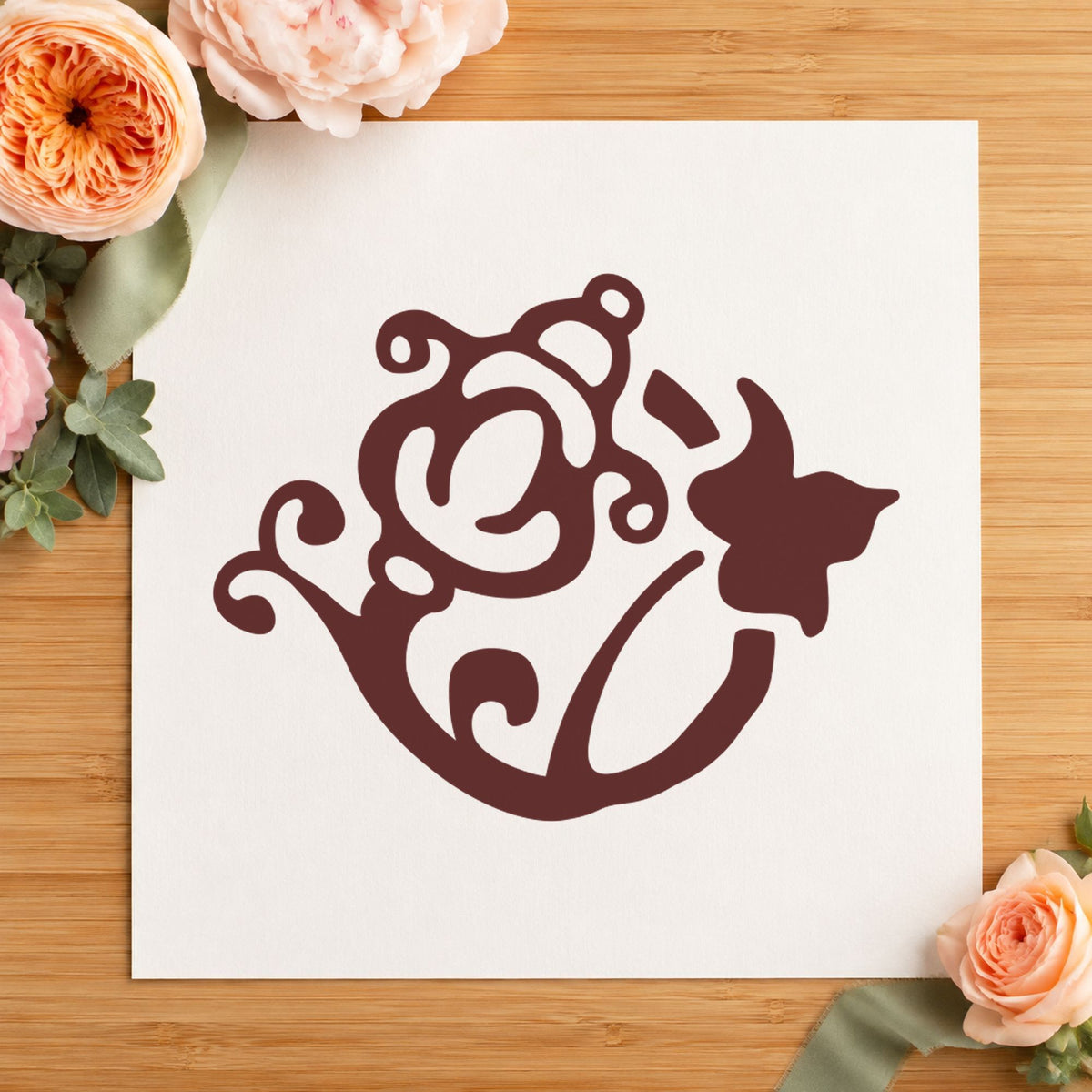 Flower and Watering Can Rubber Stamp impression in brown ink on white paper in a styled craft setting.
