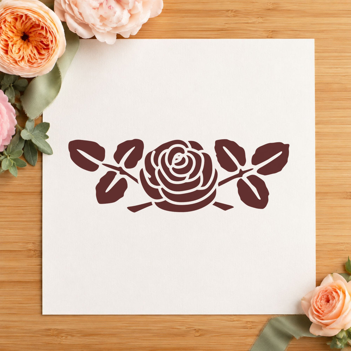Rose with Leaves Rubber Stamp Small impression in brown ink on white paper in a styled craft setting.