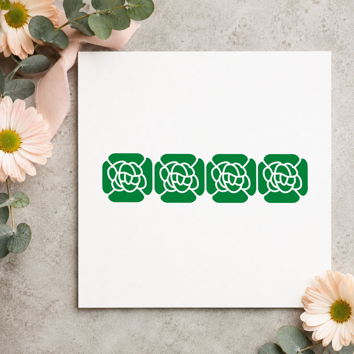 Four Solid Flowers Border Rubber Stamp impression in green ink on white paper in a styled craft setting.