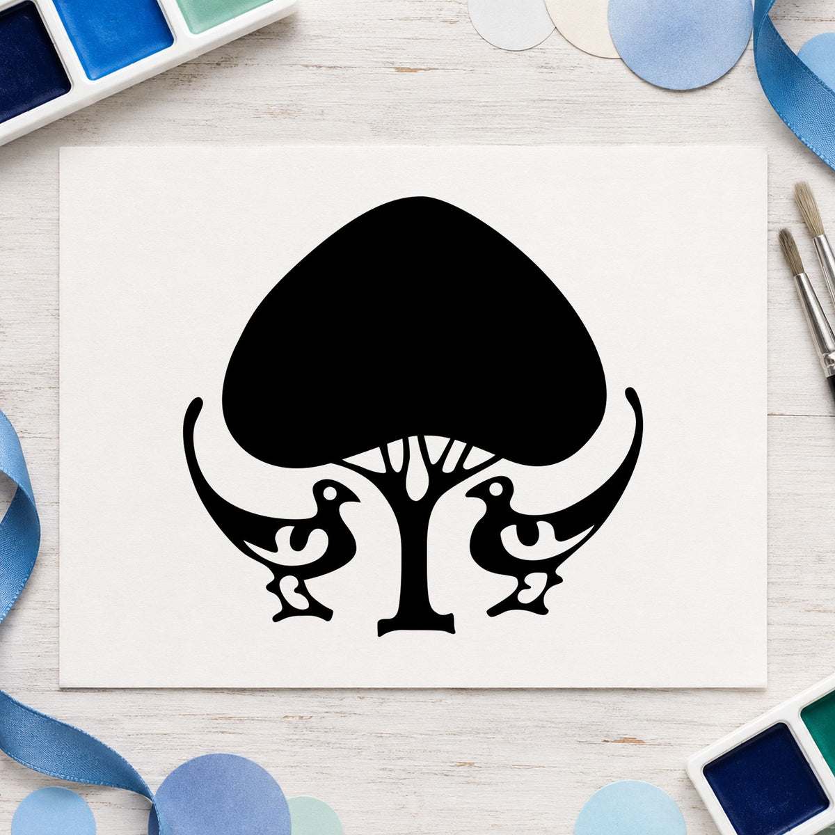 Leafy Tree and Birds Rubber Stamp impression in black ink on white paper in a styled craft setting.