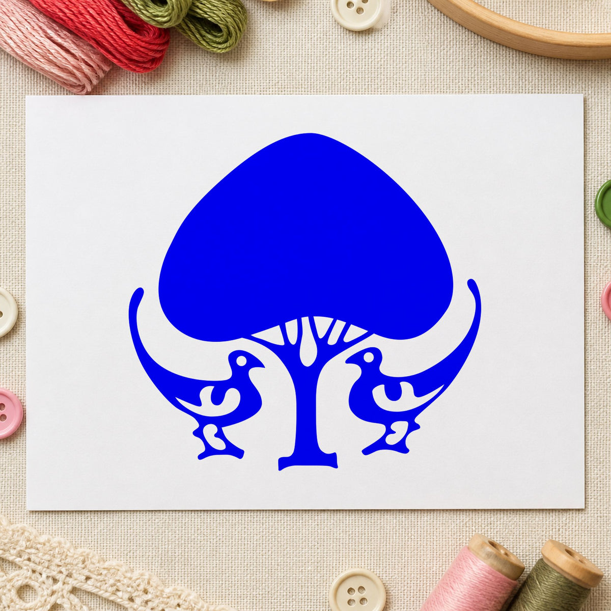 Leafy Tree and Birds Rubber Stamp impression in blue ink on white paper in a styled craft setting.