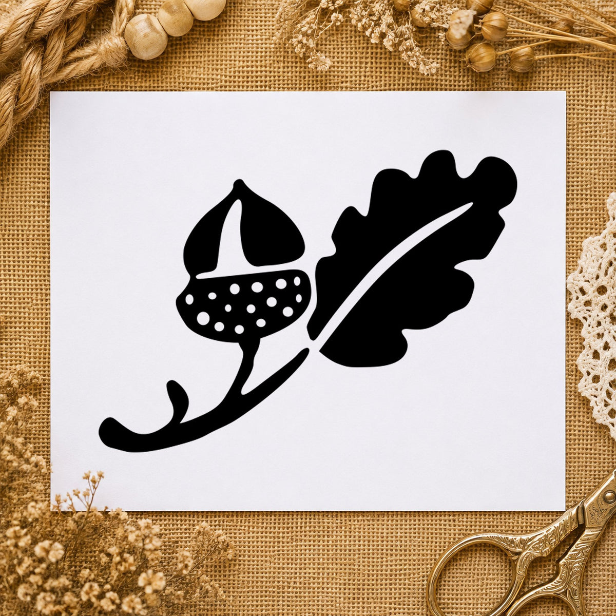 Black impression from a acorn rubber stamp, featuring the solid acorn and leaf design on white paper.